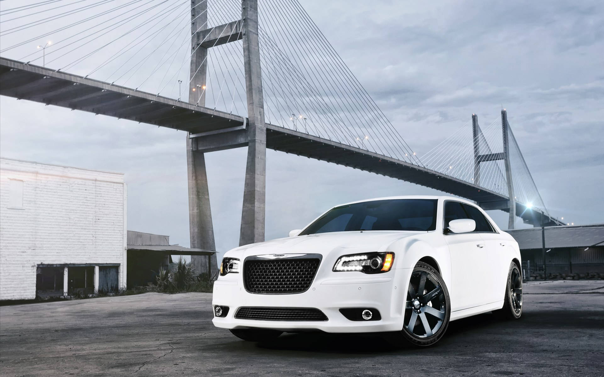 2012 Chrysler 300 SRT8 壁紙 — 一架時尚的白色豪華轎車停泊在一個巨大的現代斜拉橋下，天氣陰沉。