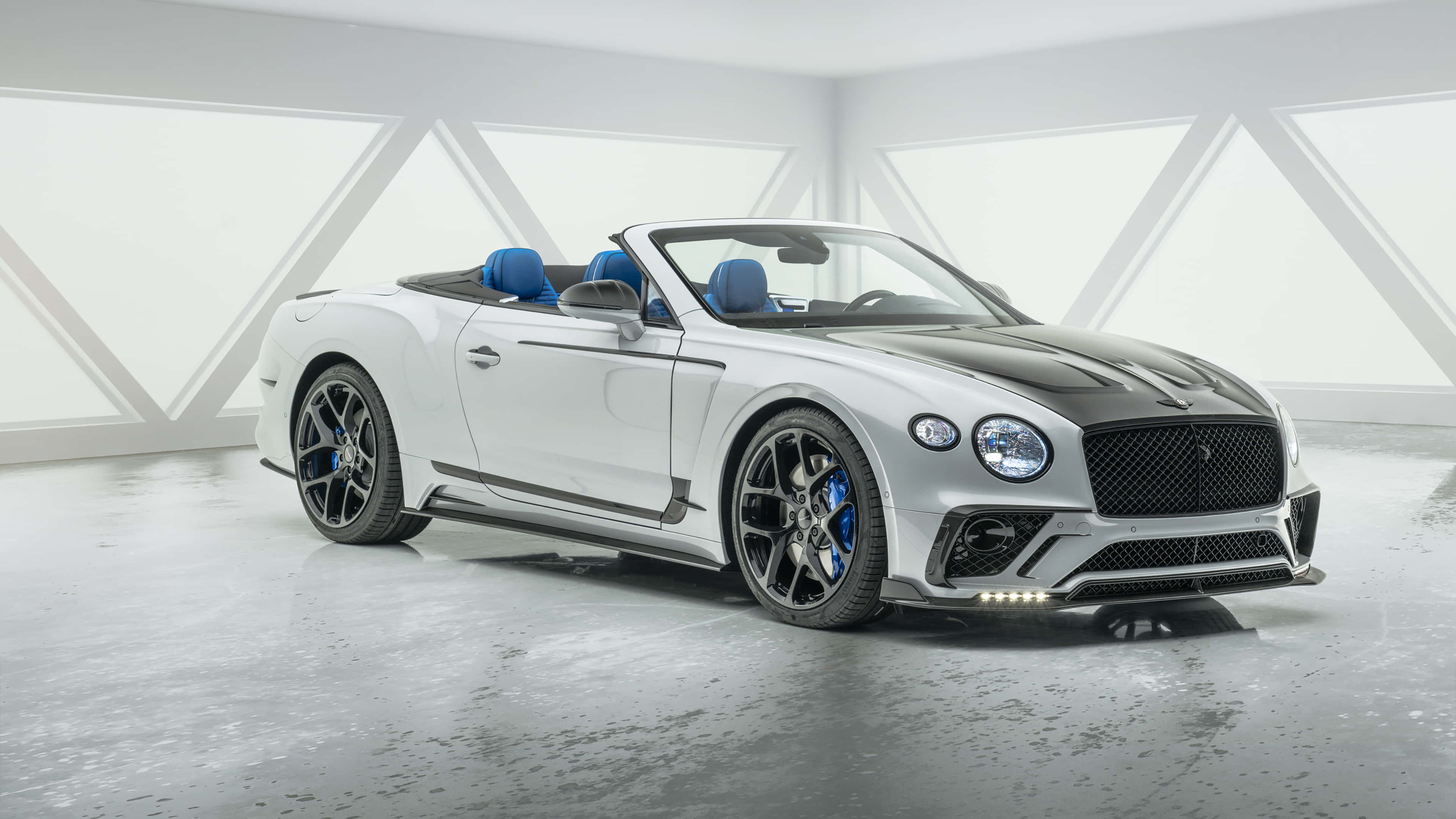 Bentley Continental Gt 桌布 壁紙 — 一架時尚的白色賓利開篷車，配備藍色內飾和黑色飾邊，在簡約的白色幾何工作室中展示。