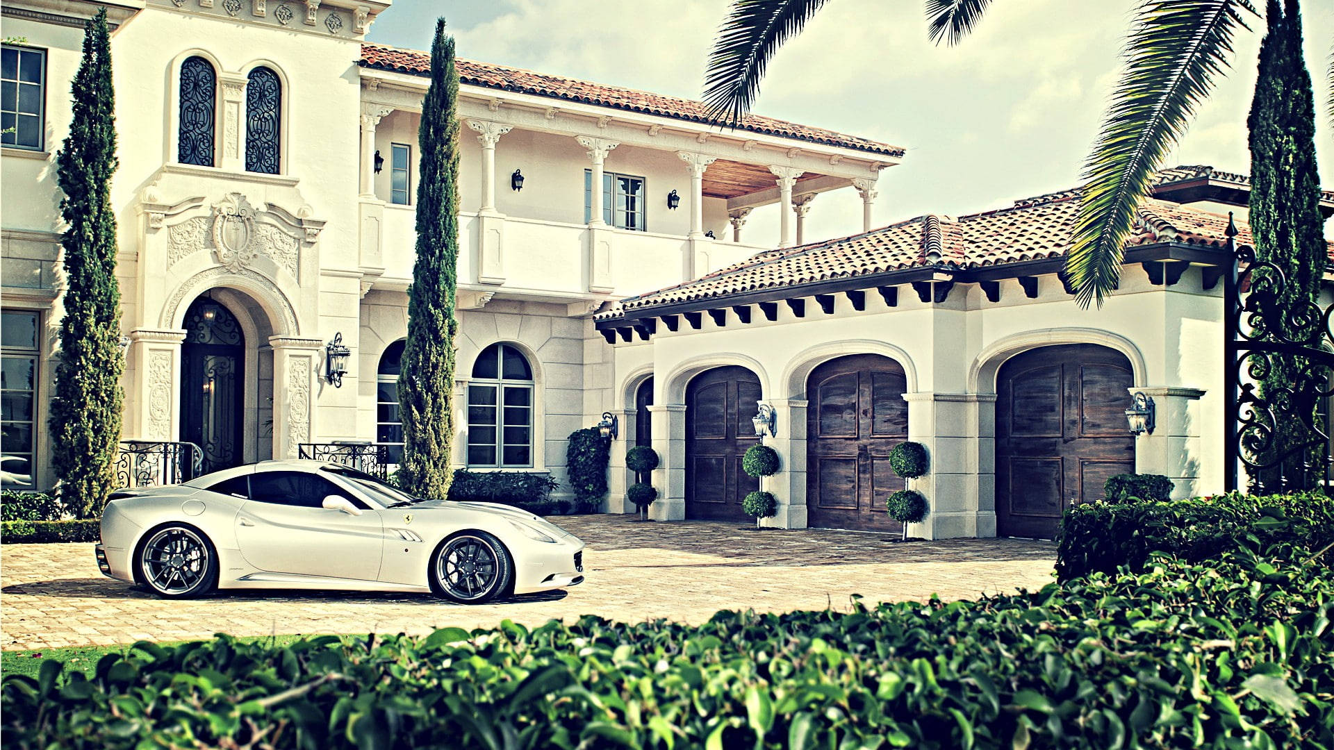 Mansion 桌布 壁紙 — 一架時尚的白色跑車停在一棟宏偉的地中海風格豪宅前，豪宅有陶土瓦屋頂和高大的柏樹。