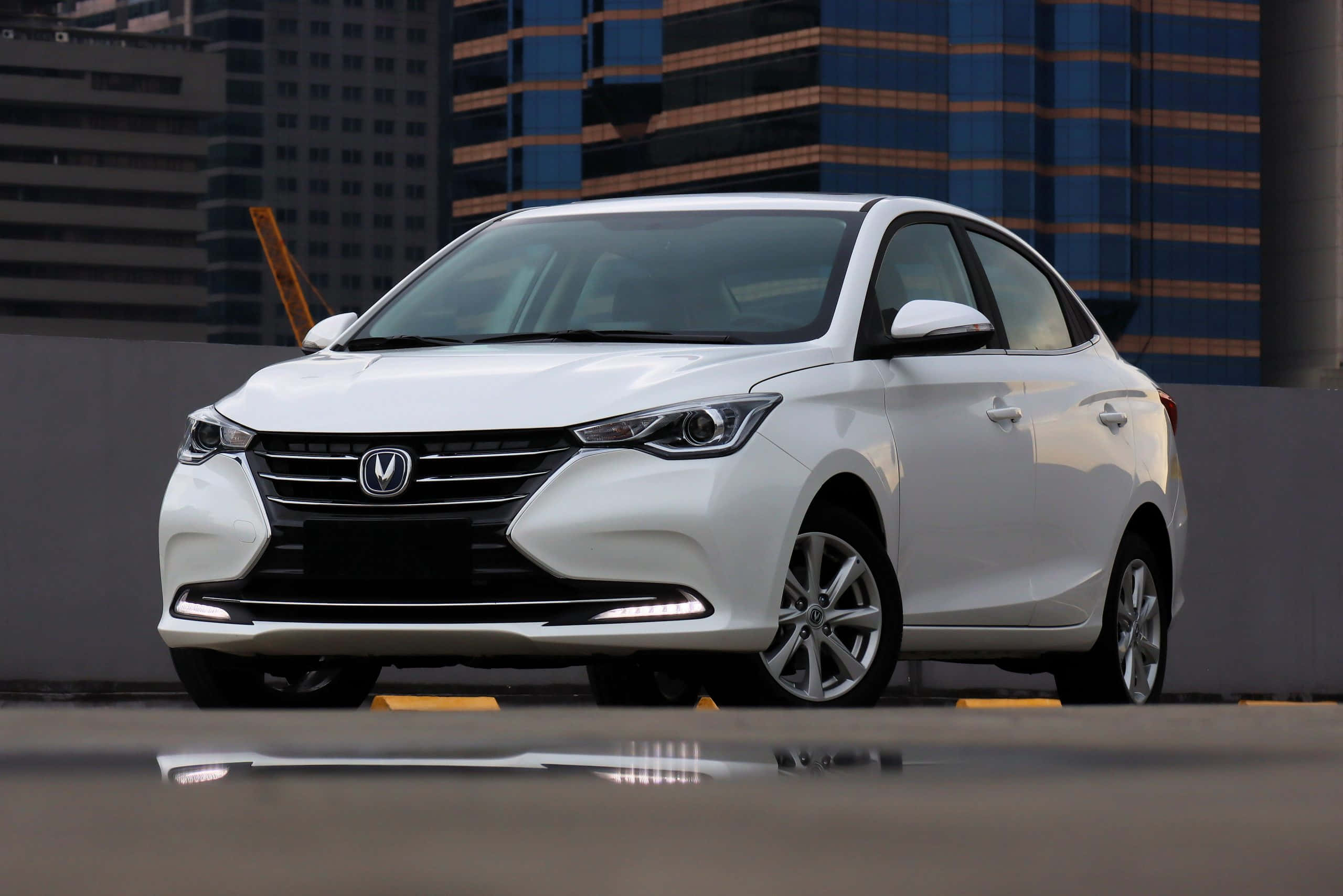 Changan 桌布 壁紙 — 一架時尚的白色轎車停泊在濕漉漉的城市屋頂上，背後現代摩天大樓倒映在水窪中。