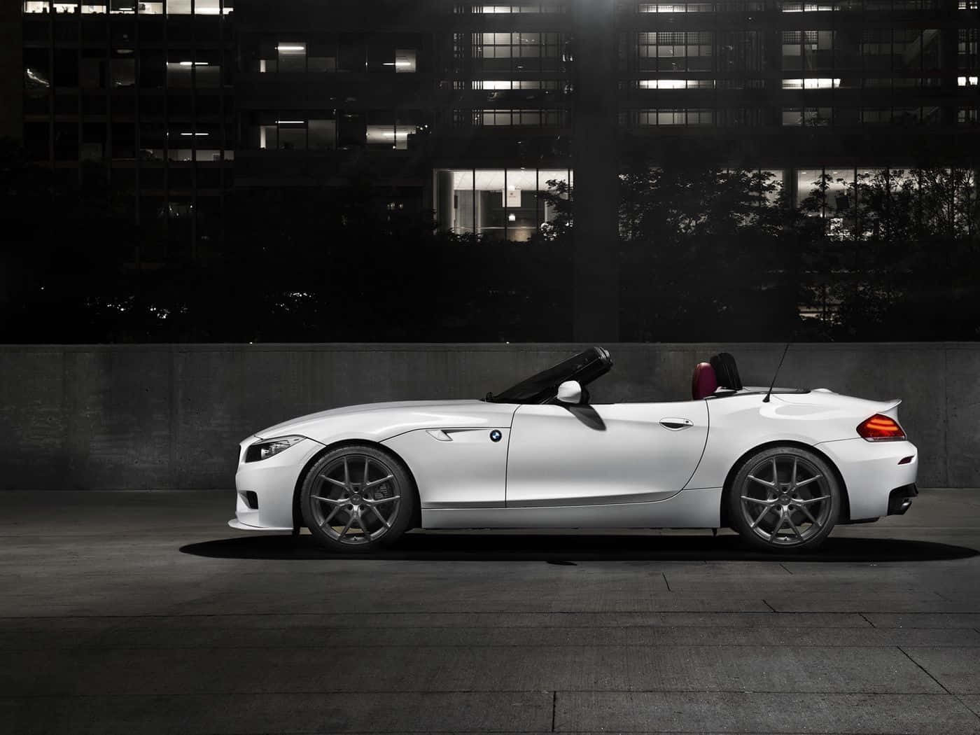Bmw Z4 桌布 壁紙 — 一架時尚的白色開篷跑車在夜晚停泊於燈火通明的城市建築背景下。