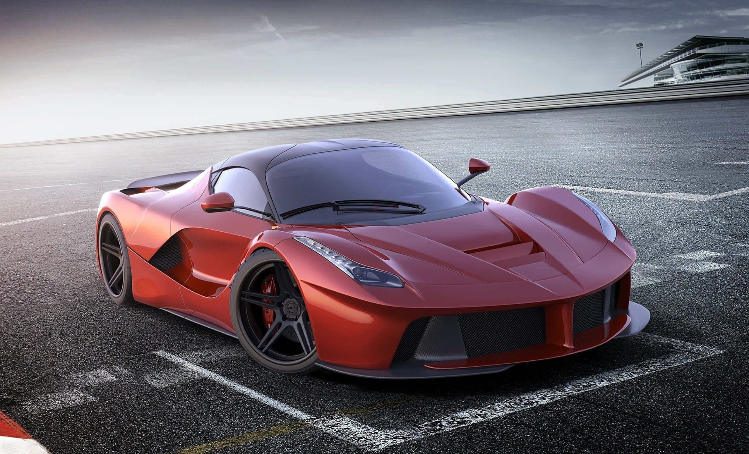 Ferrari Laferrari 桌布 壁紙 — 一架時尚的紅色法拉利 LaFerrari 停泊在賽車場上，天空多雲，遠處有看台。