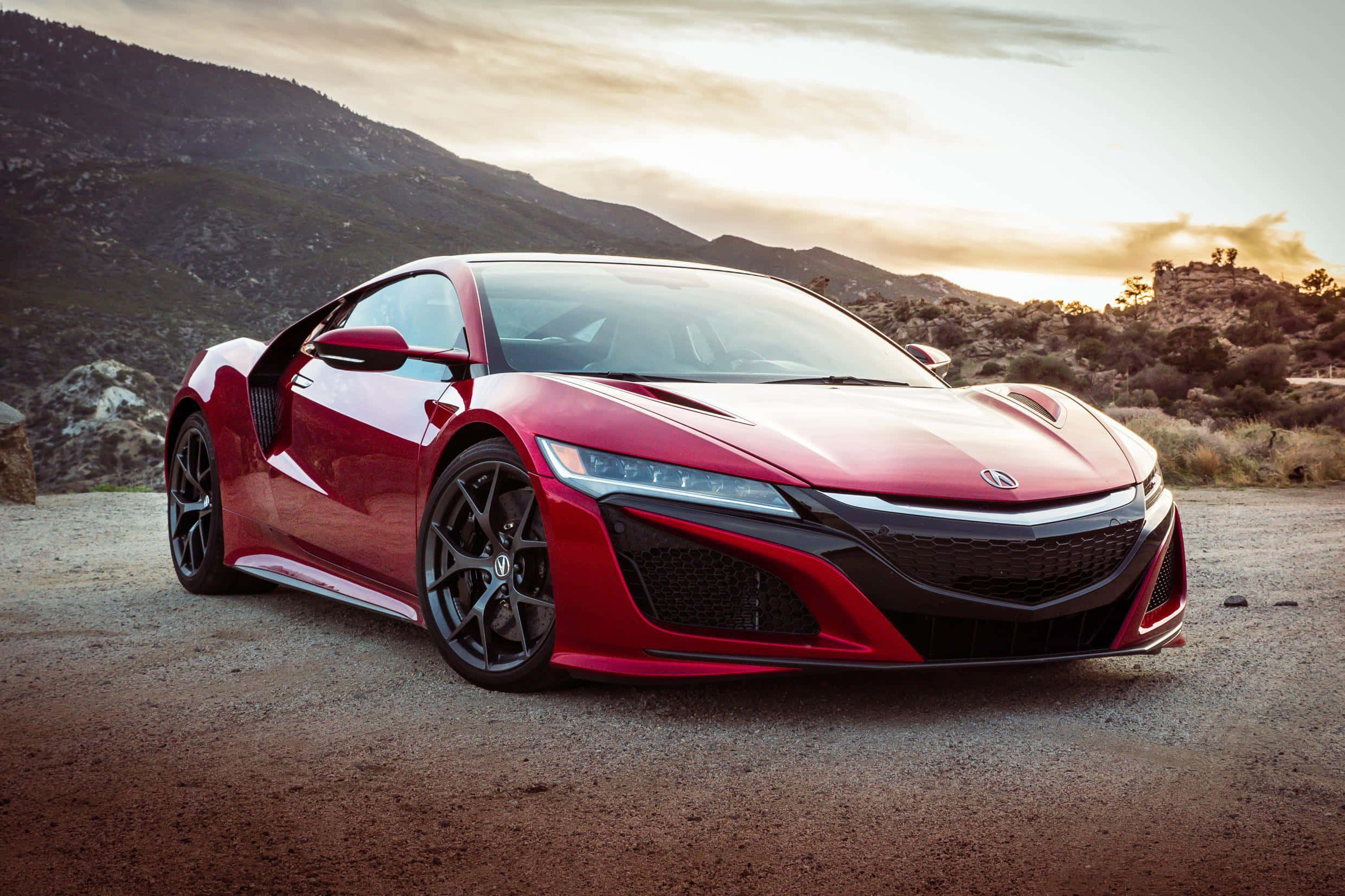 Acura Nsx 桌布 壁紙 — 一架時尚的紅色跑車停泊在碎石路上，背景是日落時分的山脈。