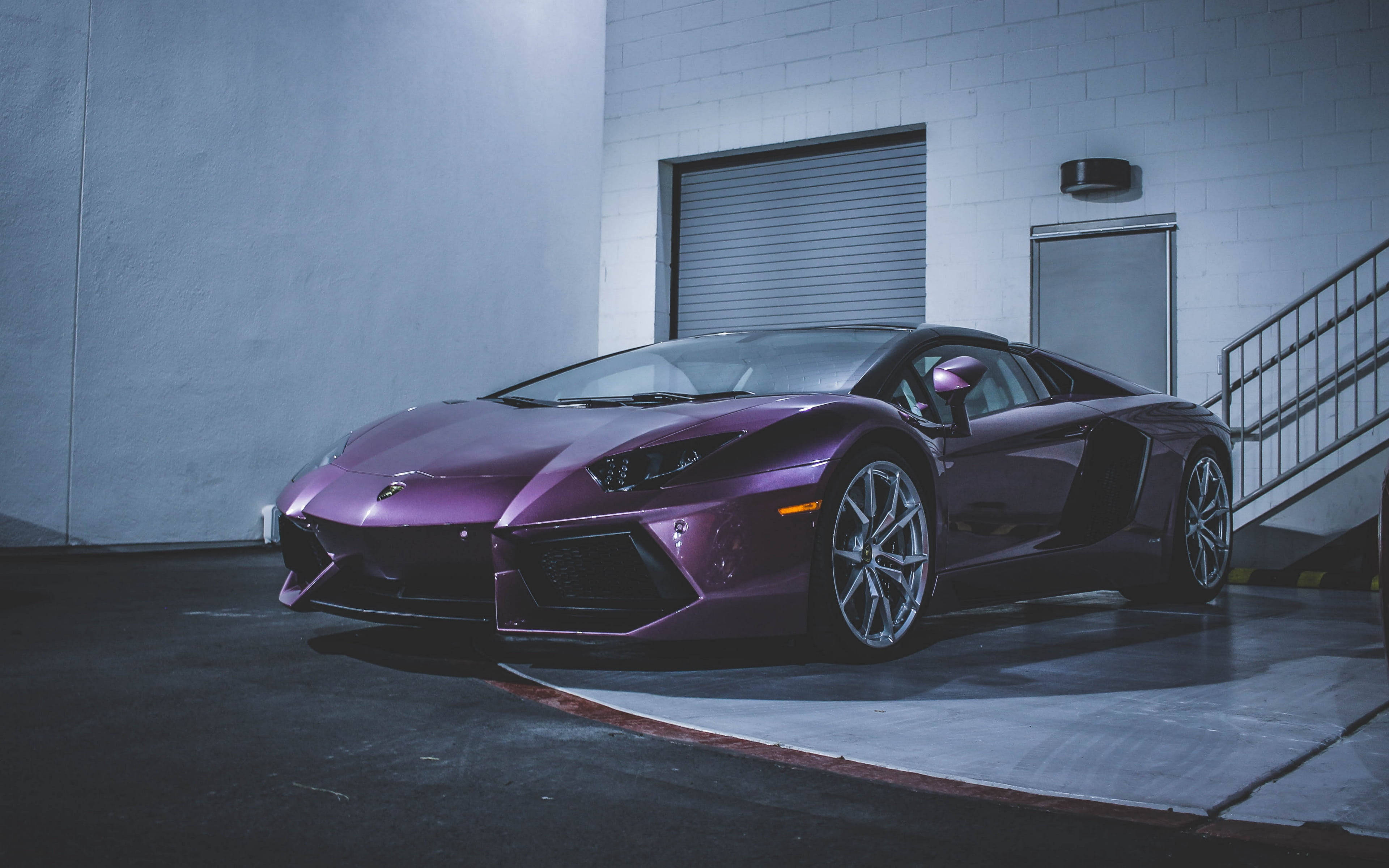 Sports Car 桌布 壁紙 — 一架時尚的紫色林寶堅尼Aventador停泊在光線昏暗的工業車庫，內有混凝土牆和金屬樓梯。