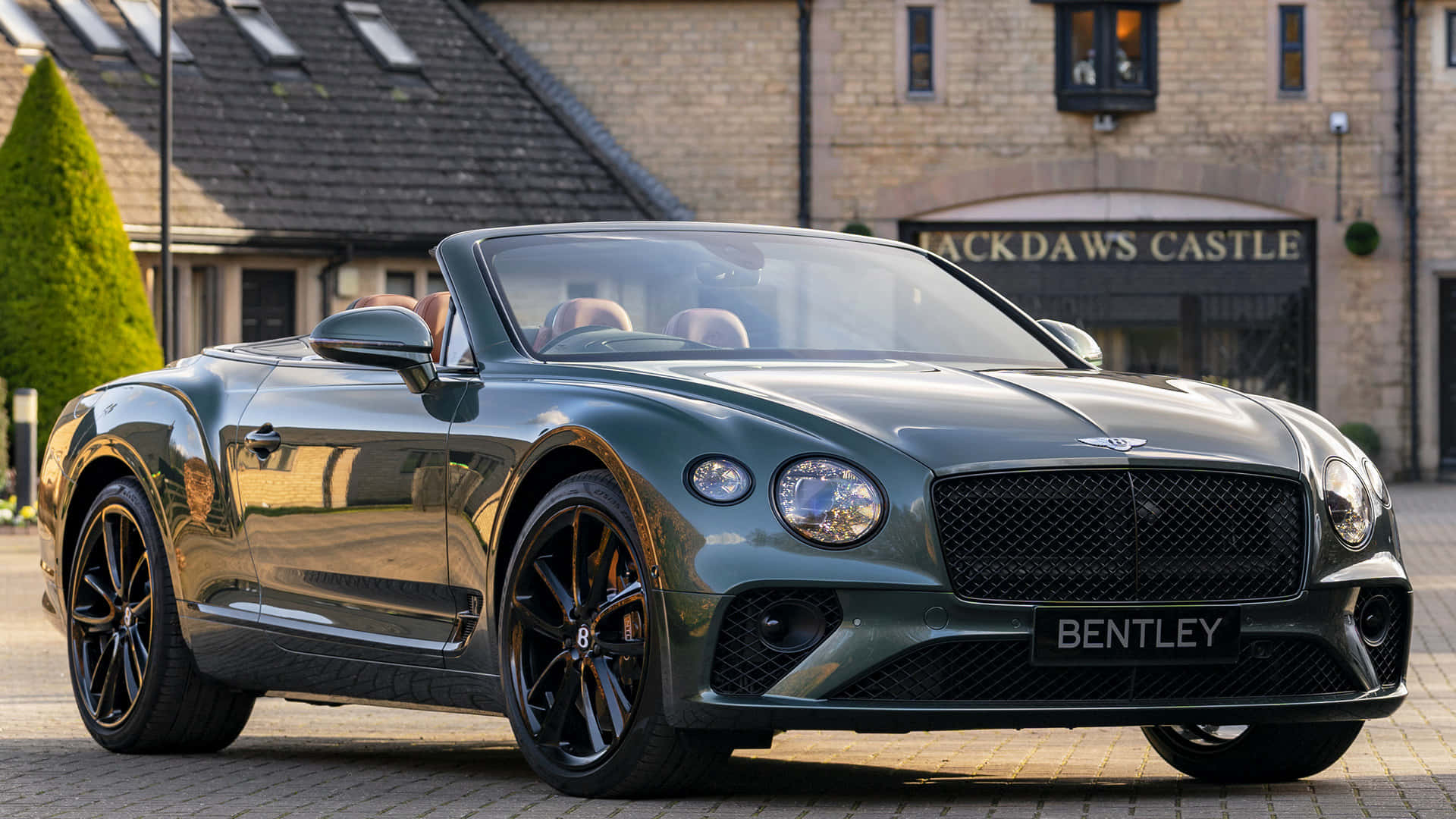 Bentley Continental Gt Convertible 桌布 壁紙 — 一架時尚的綠色賓利開篷車停泊在傑克道斯城堡前的鵝卵石車道上，陽光在其拋光表面上反射。