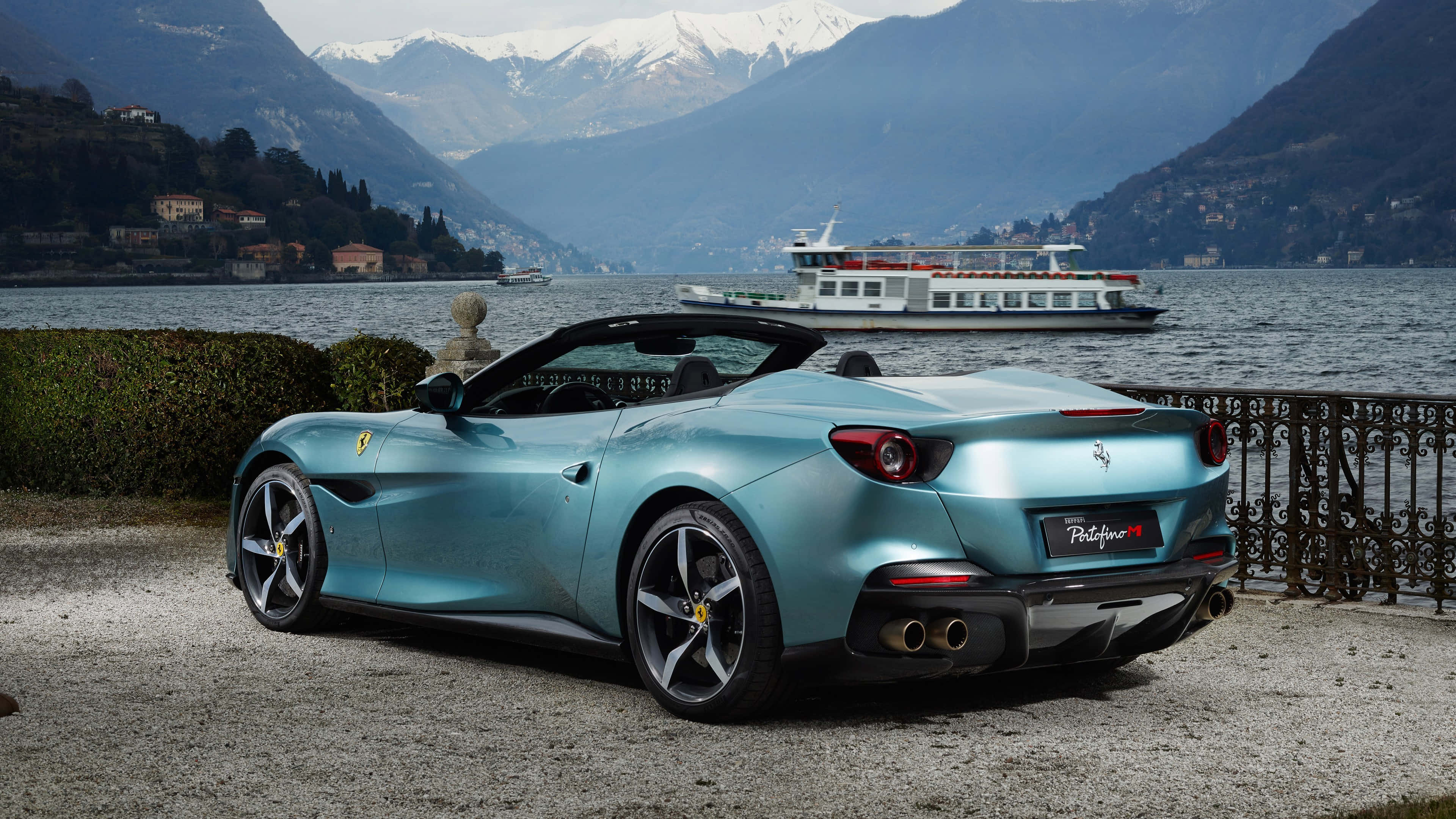 Ferrari Portofino 桌布 壁紙 — 一架時尚的藍綠色法拉利Portofino停泊在湖邊，背景是白雪皚皚的山脈和遊輪。