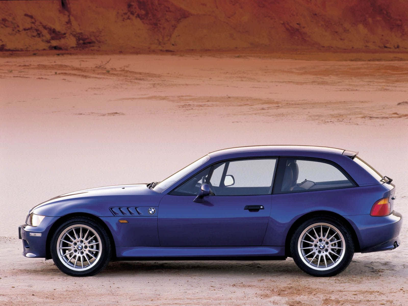 Bmw Z3 桌布 壁紙 — 一架時尚的藍色BMW M3雙門轎跑車停泊在晴朗天空下廣闊的沙漠平原上。