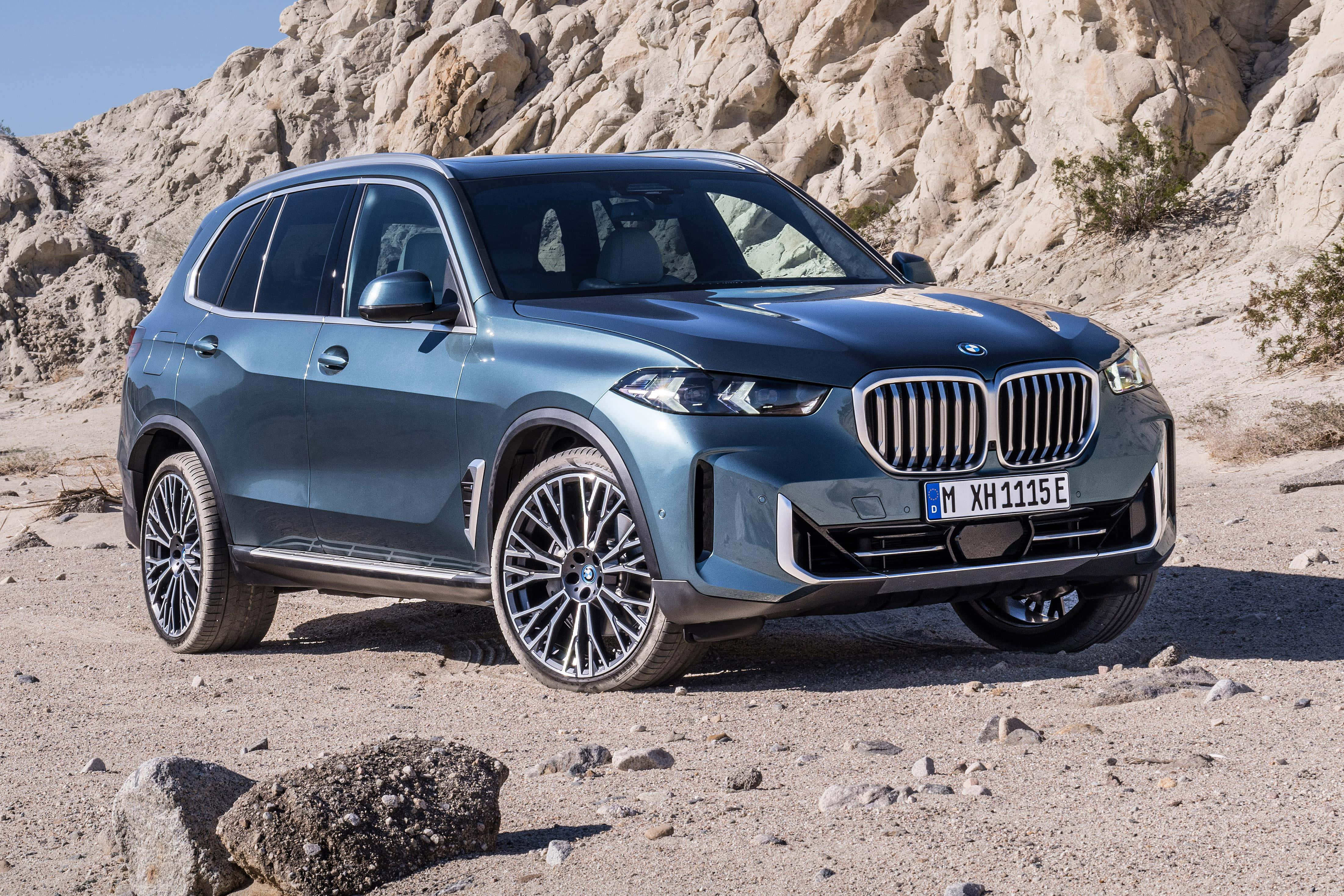 Bmw X5 桌布 壁紙 — 一架時尚的藍色BMW X5 SUV停泊在岩石沙漠地形上，在明亮的日光下。