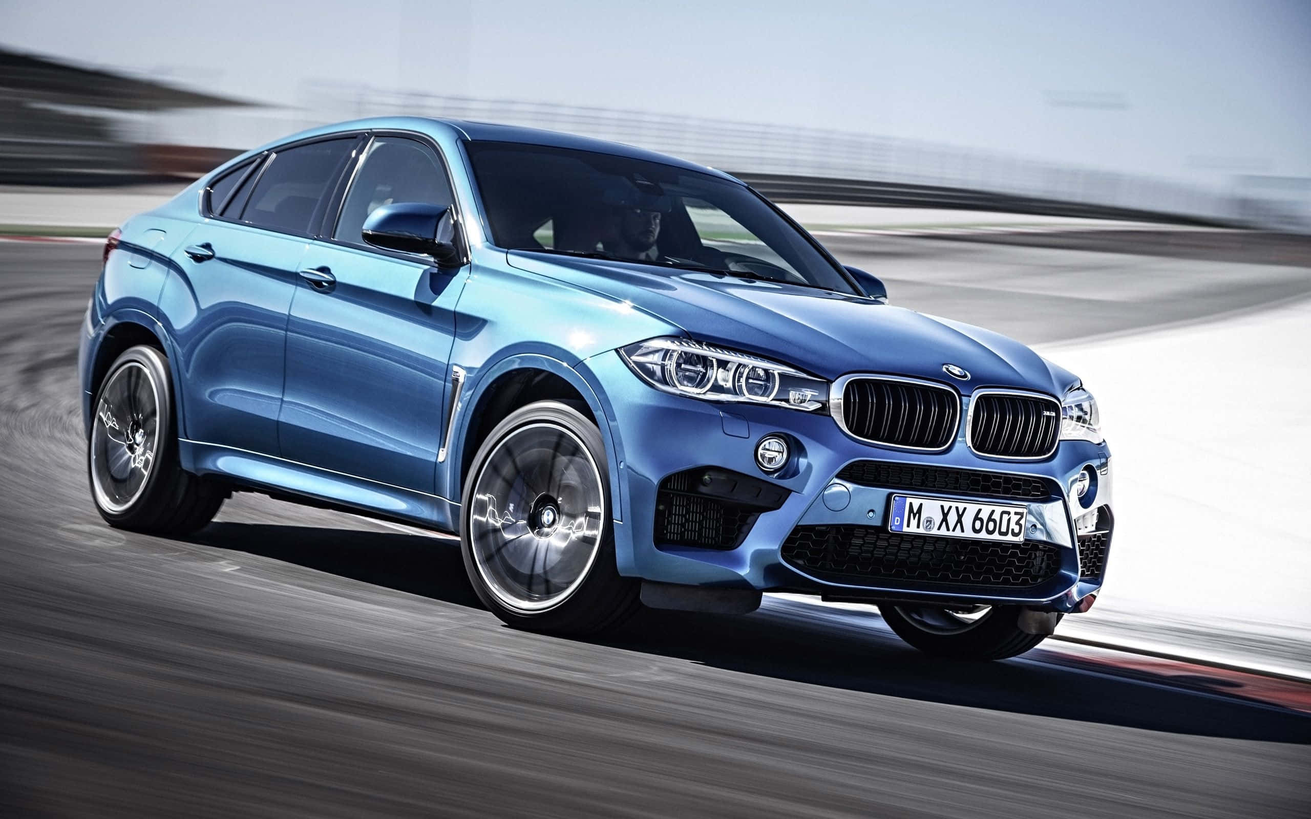 Bmw X6 桌布 壁紙 — 一架時尚的藍色BMW X6 M在賽道上疾馳，動態模糊效果突顯其卓越性能。