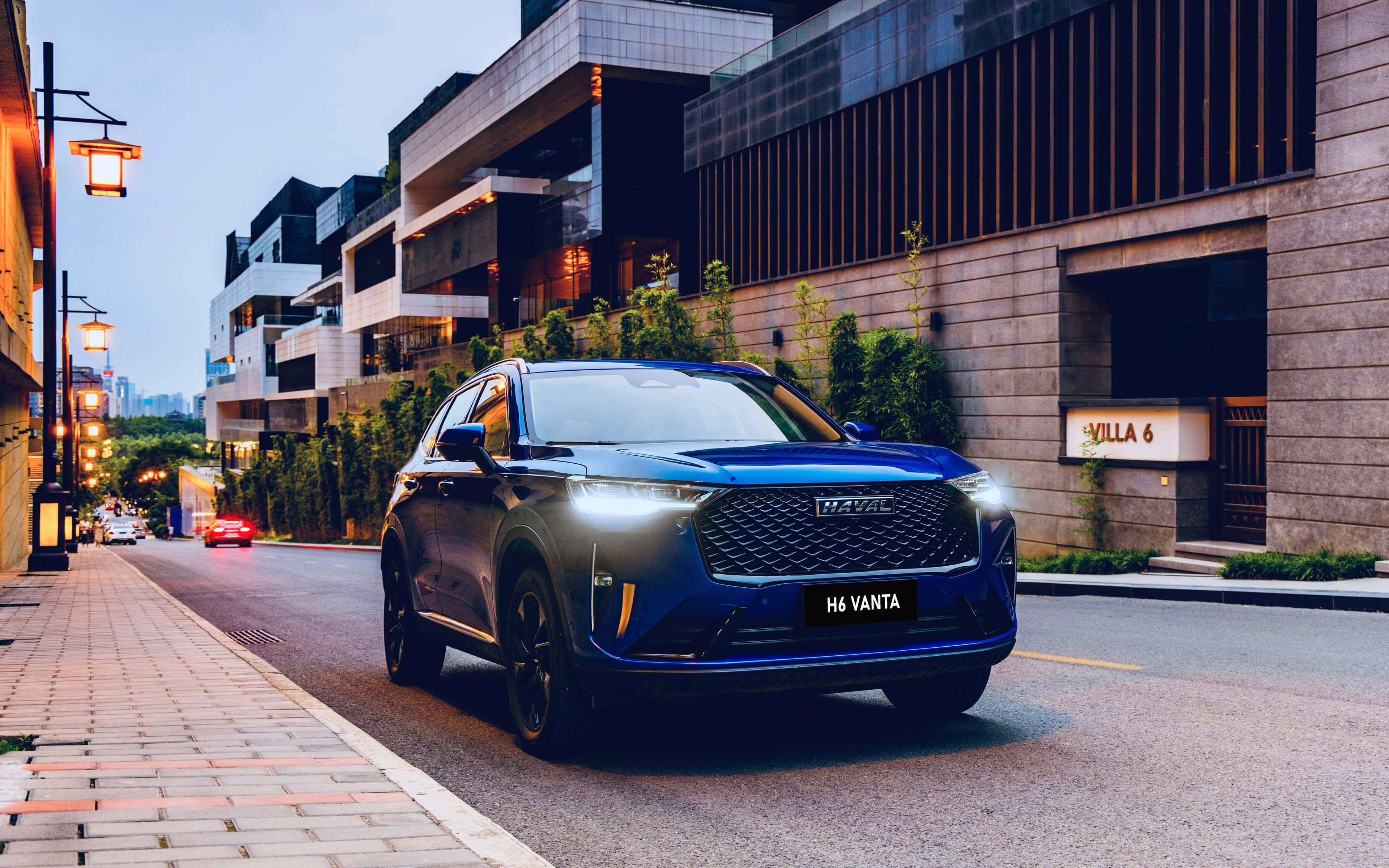 Haval 桌布 壁紙 — 一架時尚的藍色H6 Vanta SUV在黃昏時分行駛在現代城市街道上，兩旁有發光的街燈和當代建築。