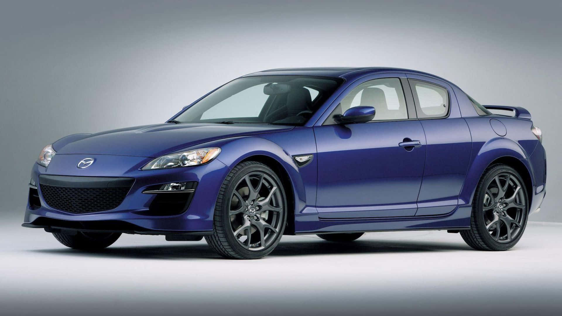 Mazda Rx-8 桌布 壁紙 — 一架時尚的藍色Mazda RX-8跑車配黑色輪圈，在簡約的攝影棚環境中展示。
