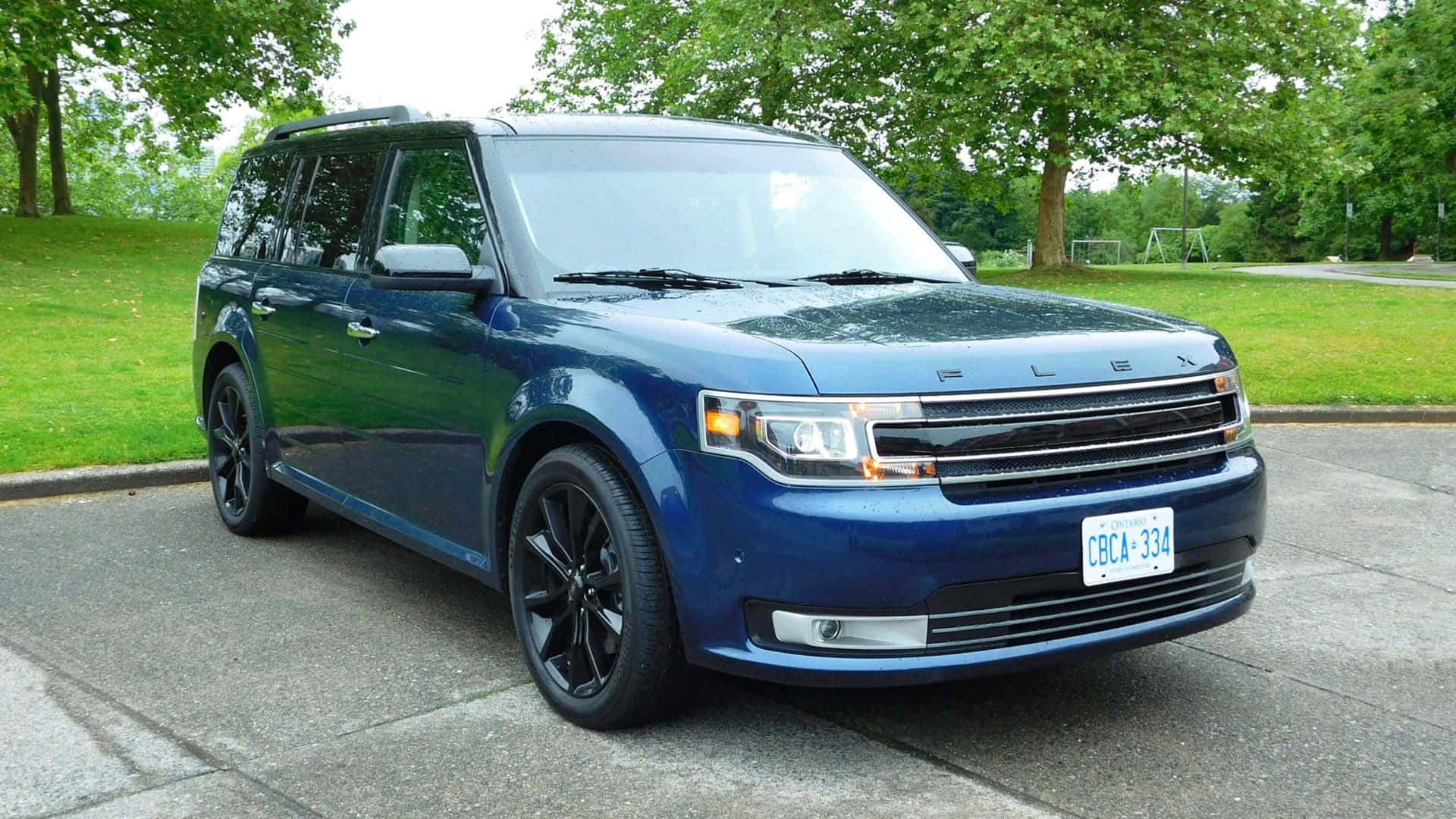 Ford Flex 桌布 壁紙 — 一架時尚的藍色福特Flex SUV停泊在鋪砌的車道上，背景有茂密的綠樹和草地。