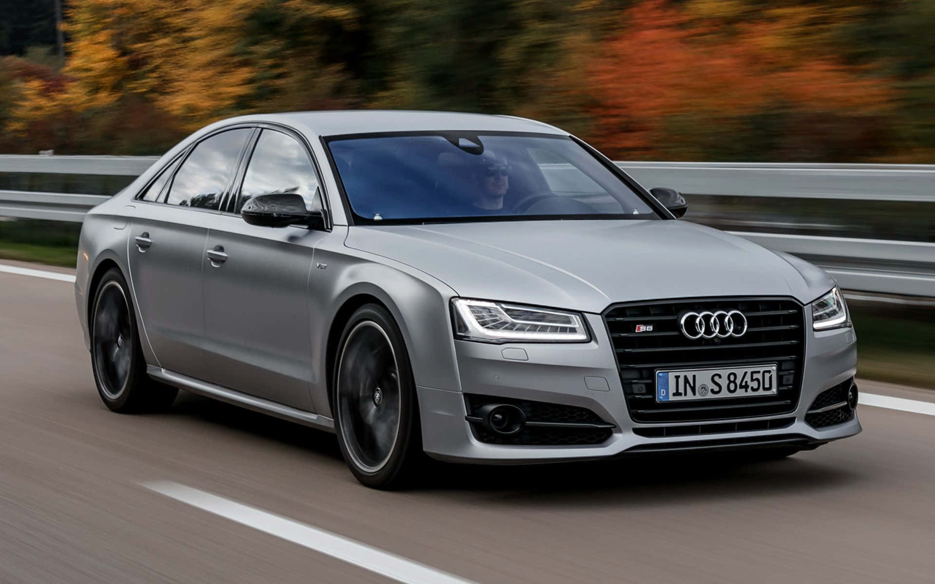 Audi S8 桌布 壁紙 — 一架時尚的銀色 Audi S8 轎車在高速公路上飛馳，背景中的秋葉模糊不清。
