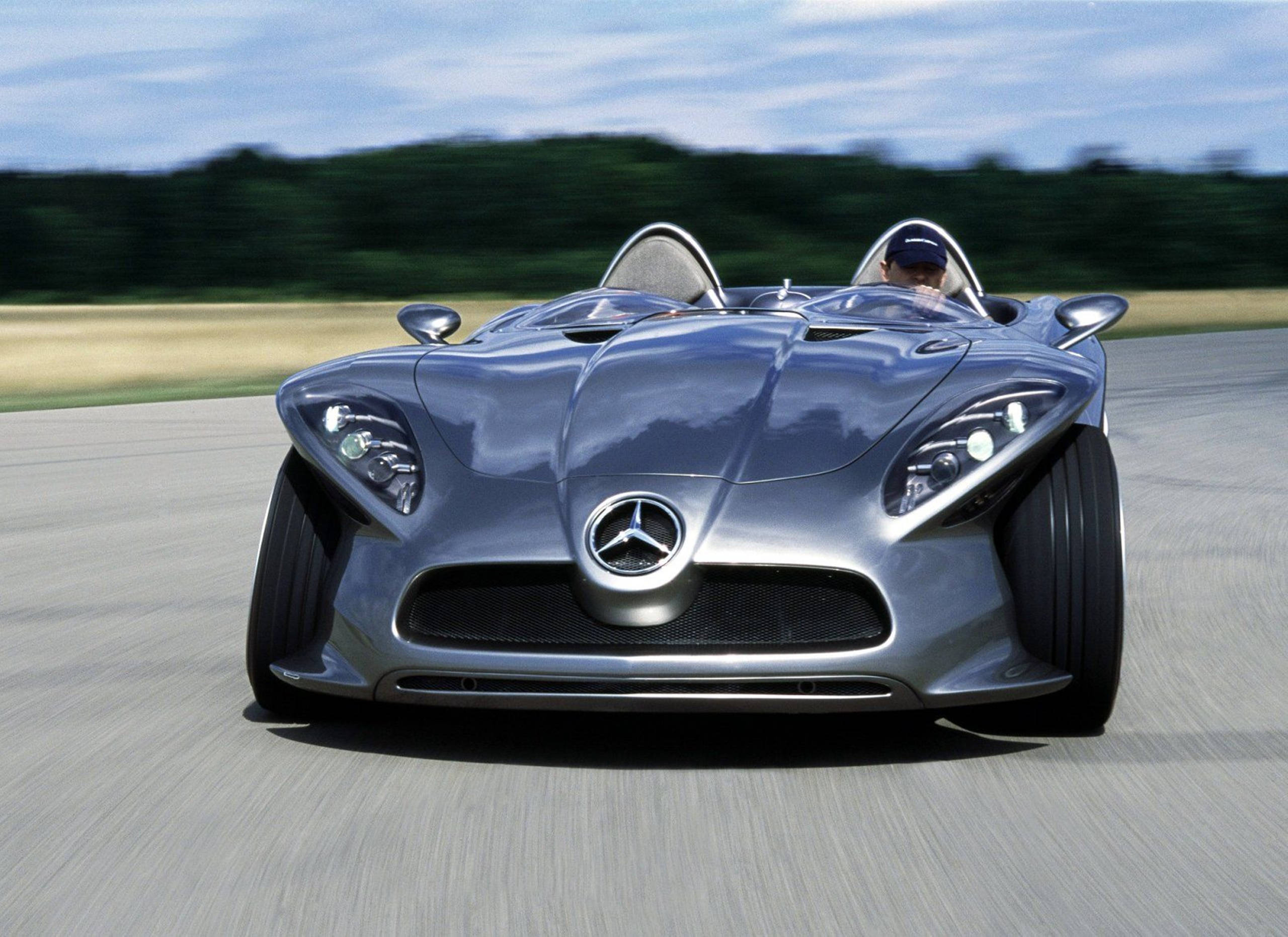HD 桌布 壁紙 — 一架時尚的銀色 Mercedes-Benz 概念車在鋪砌的賽道上疾馳，背景是模糊的綠色植物。