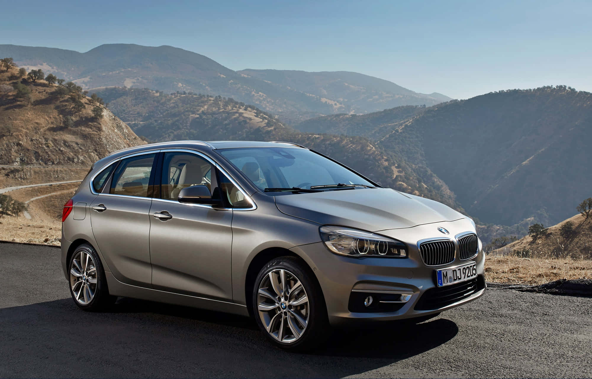Bmw 2 Series 桌布 壁紙 — 一架時尚的銀色BMW 2系Active Tourer停泊在蜿蜒的山路上，天空清澈湛藍。