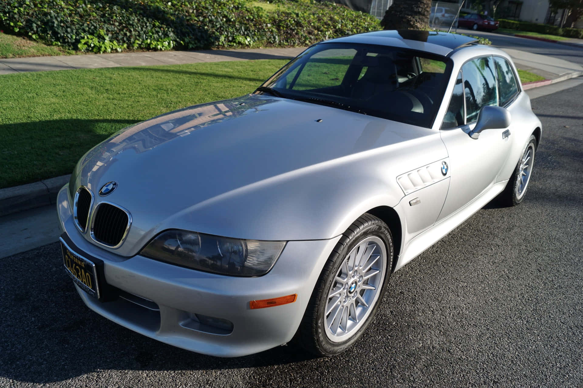 Bmw Z3 桌布 壁紙 — 一架時尚的銀色BMW Z3開篷跑車停泊在陽光明媚的住宅街道上，背景有綠草和樹籬。