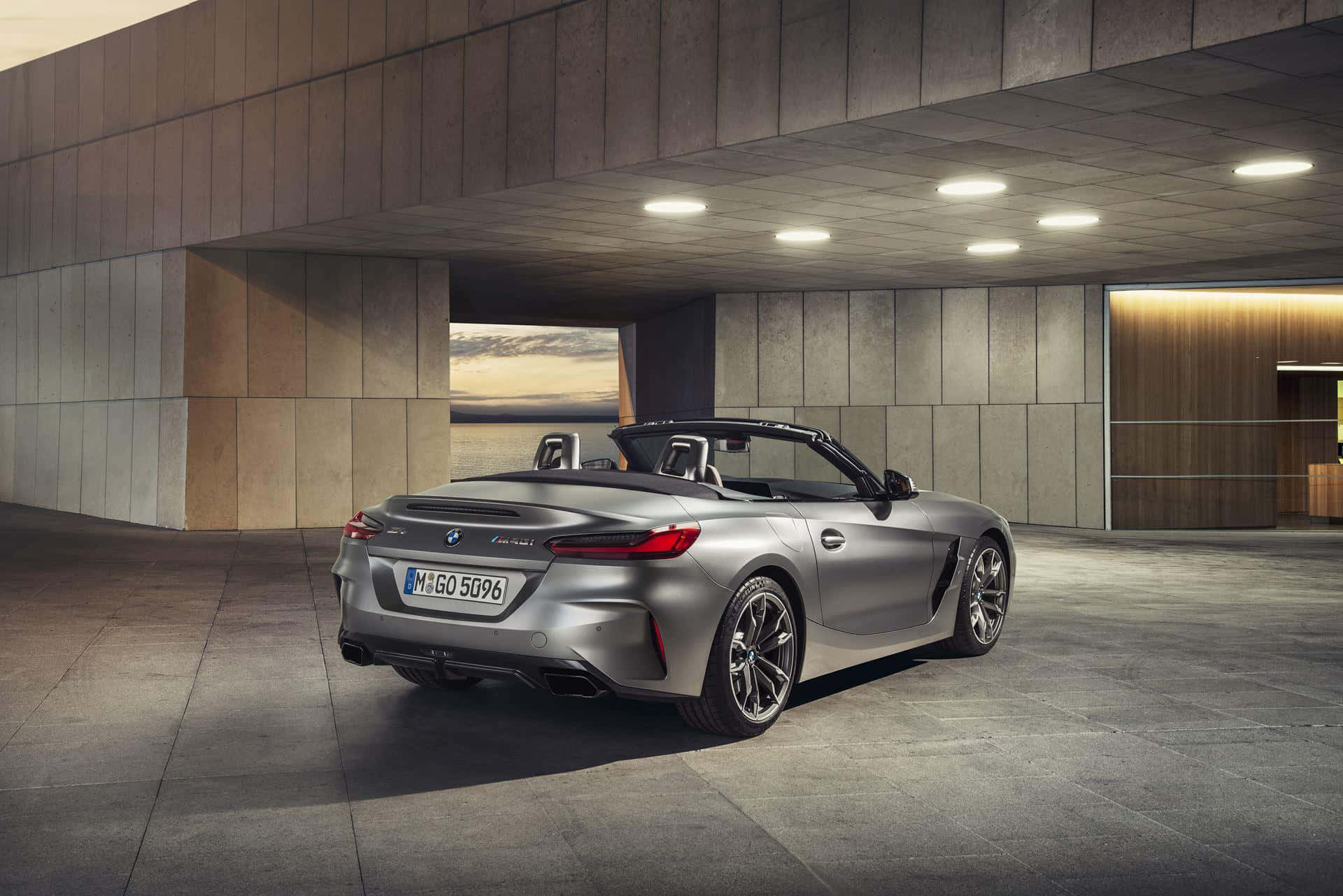 Bmw Z4 桌布 壁紙 — 一架時尚的銀色BMW Z4開篷車停泊在現代混凝土結構下，夕陽光線從開口處照射進來。