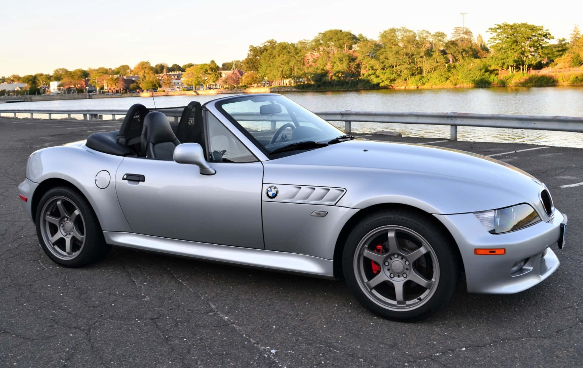 Bmw Z3 桌布 壁紙 — 一架時尚的銀色BMW Z8開篷車在黃金時段停泊在海濱，背景有樹木。