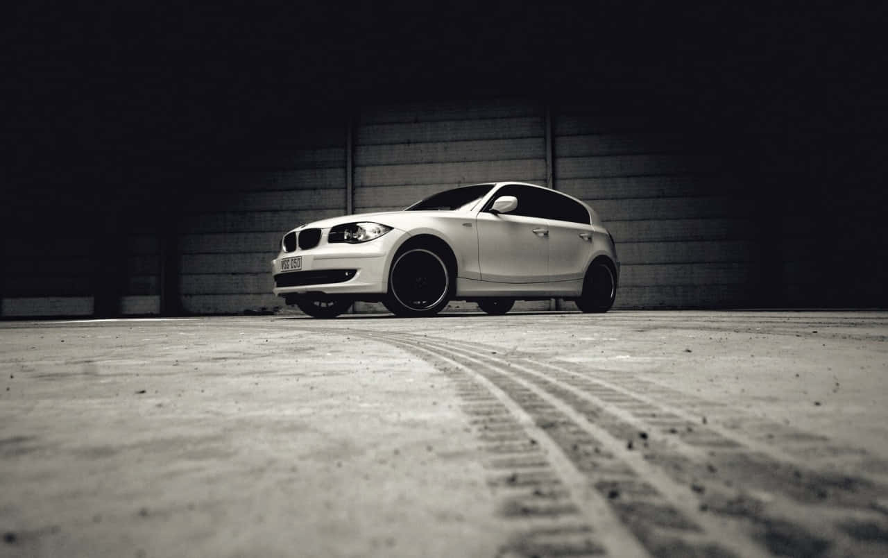 Bmw 1 Series 桌布 壁紙 — 一架時尚的銀色BMW掀背車停在昏暗的混凝土車庫中，地板上有輪胎痕跡。