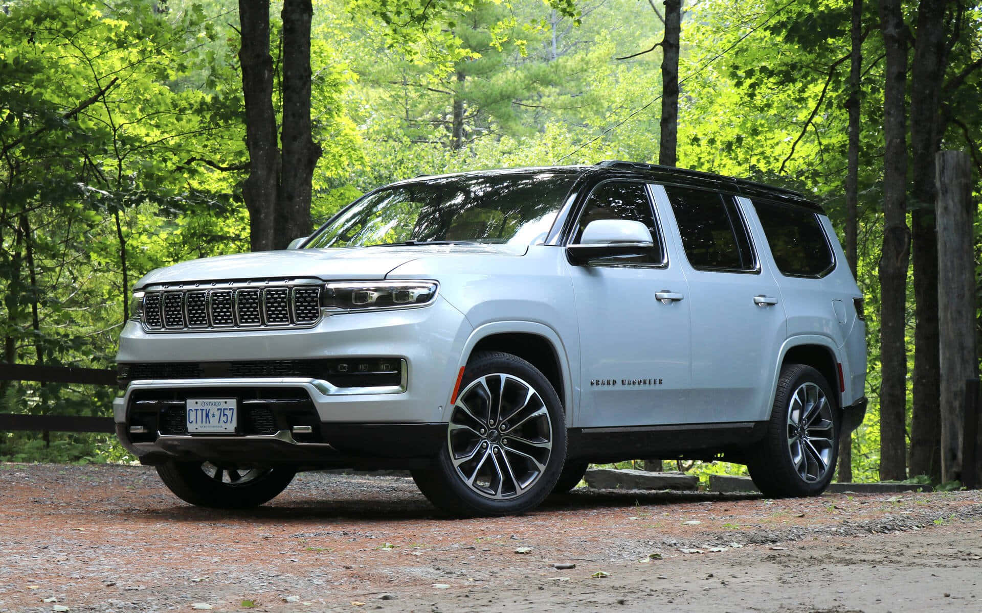 Jeep Wagoneer 桌布 壁紙 — 一架時尚的銀色Jeep Grand Wagoneer SUV停泊在泥濘小徑上，周圍是茂密的綠色森林樹木。