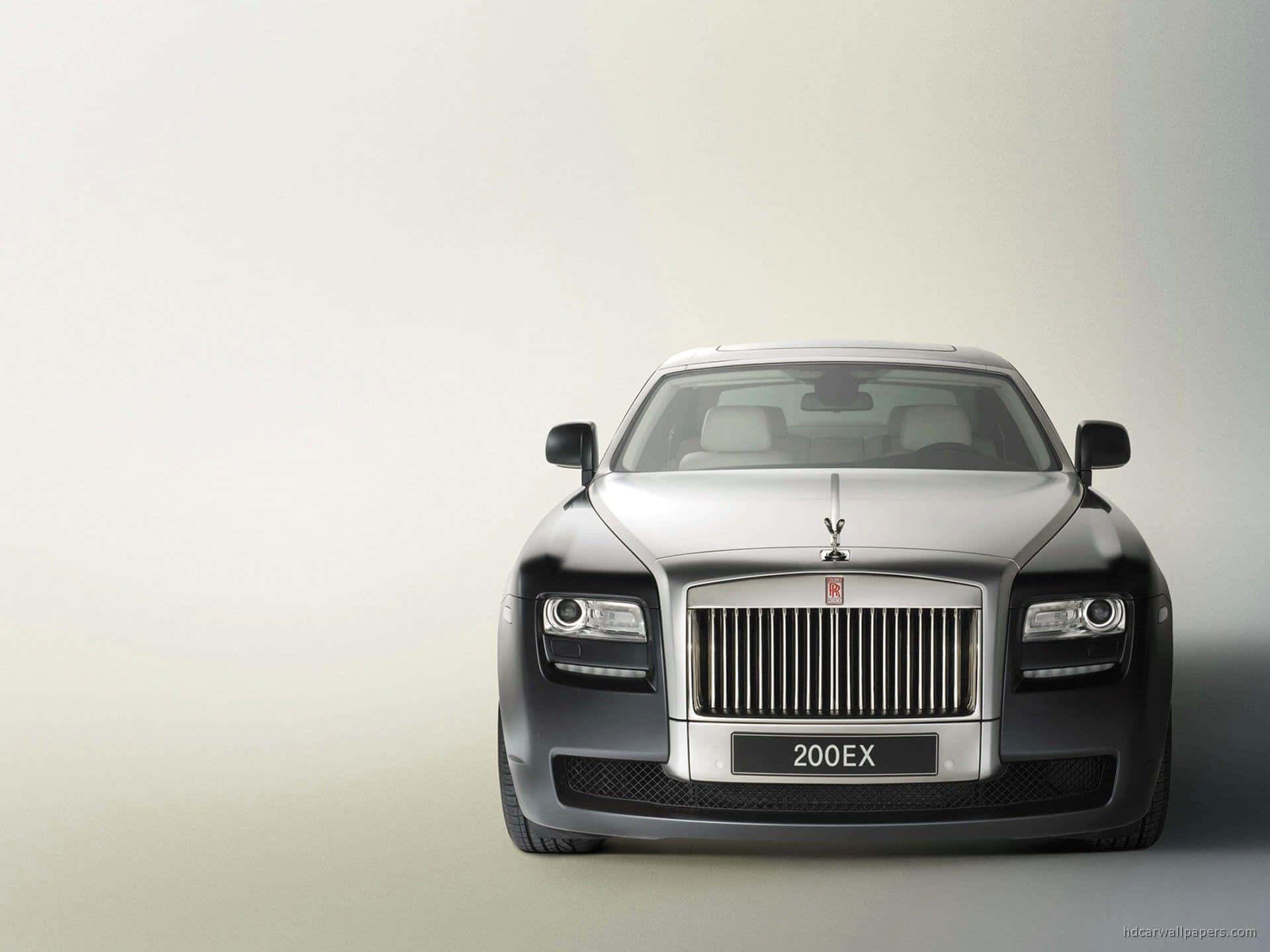 Rolls Royce 桌布 壁紙 — 一架時尚的銀色勞斯萊斯 Ghost 正面朝向簡約工作室背景，配以柔和燈光。
