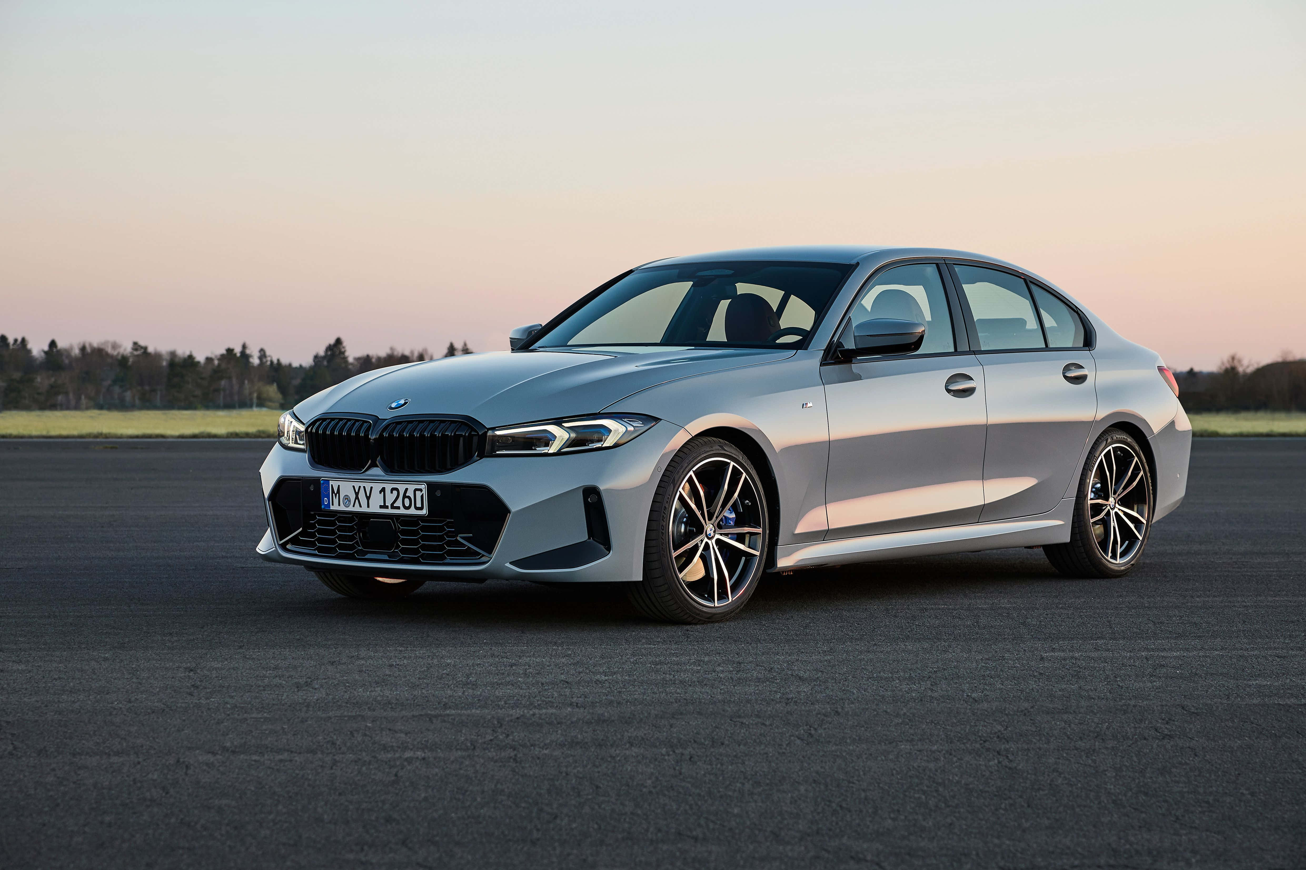 Bmw 3 Series 桌布 壁紙 — 一架時尚的銀色寶馬3系轎車停泊在日落時分的瀝青路上，背後是柔和的粉紅和橙色天空。