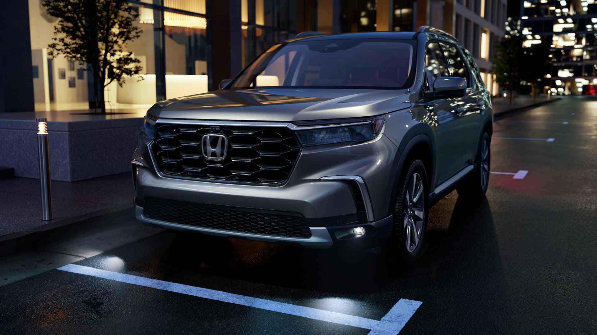 Honda Pilot 桌布 壁紙 — 一架時尚的銀色本田SUV在夜間停泊於城市街道，反射濕漉漉的路面和閃爍的建築燈光。