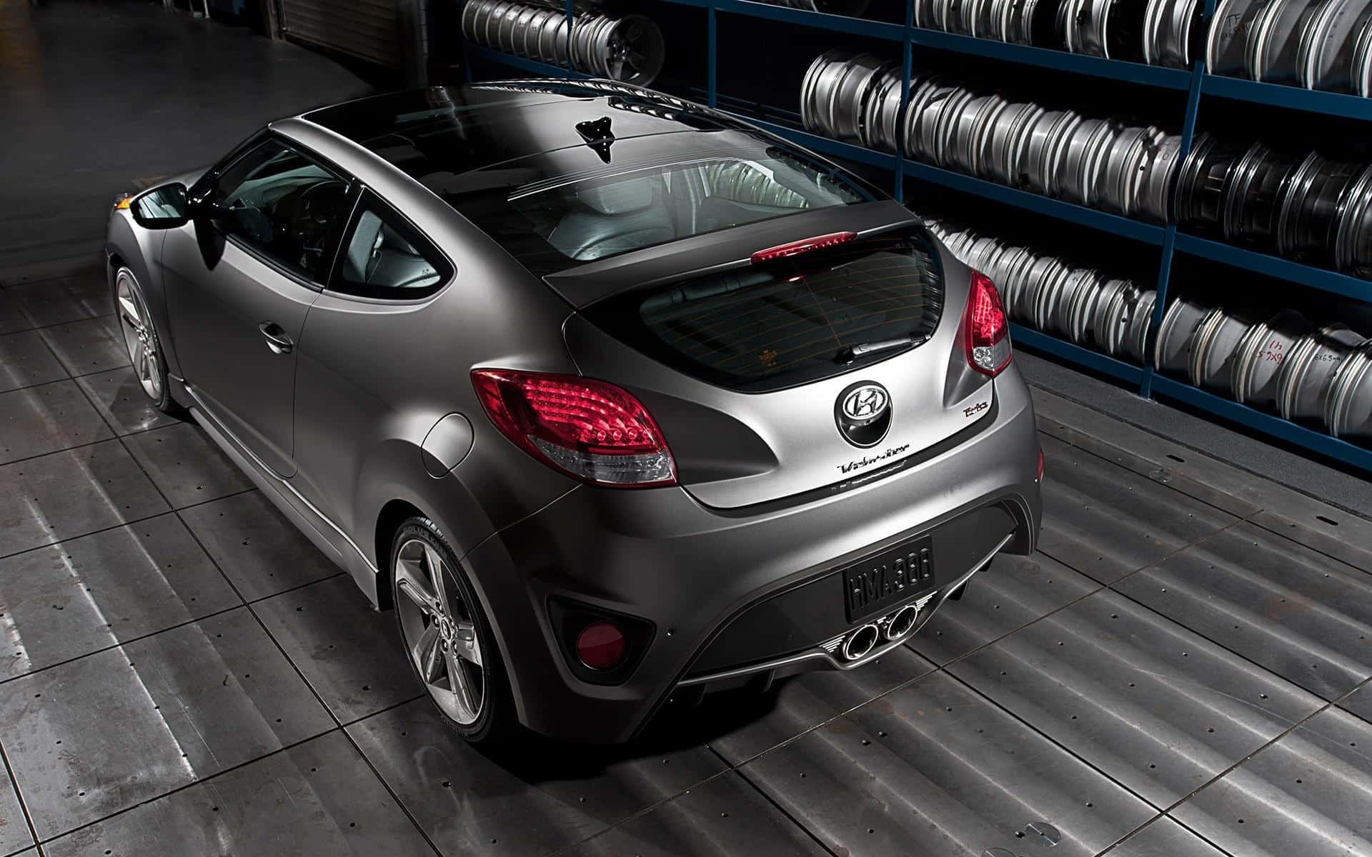 Hyundai Veloster 桌布 壁紙 — 一架時尚的銀色現代Veloster跑車停泊在倉庫內，後面有輪胎架。