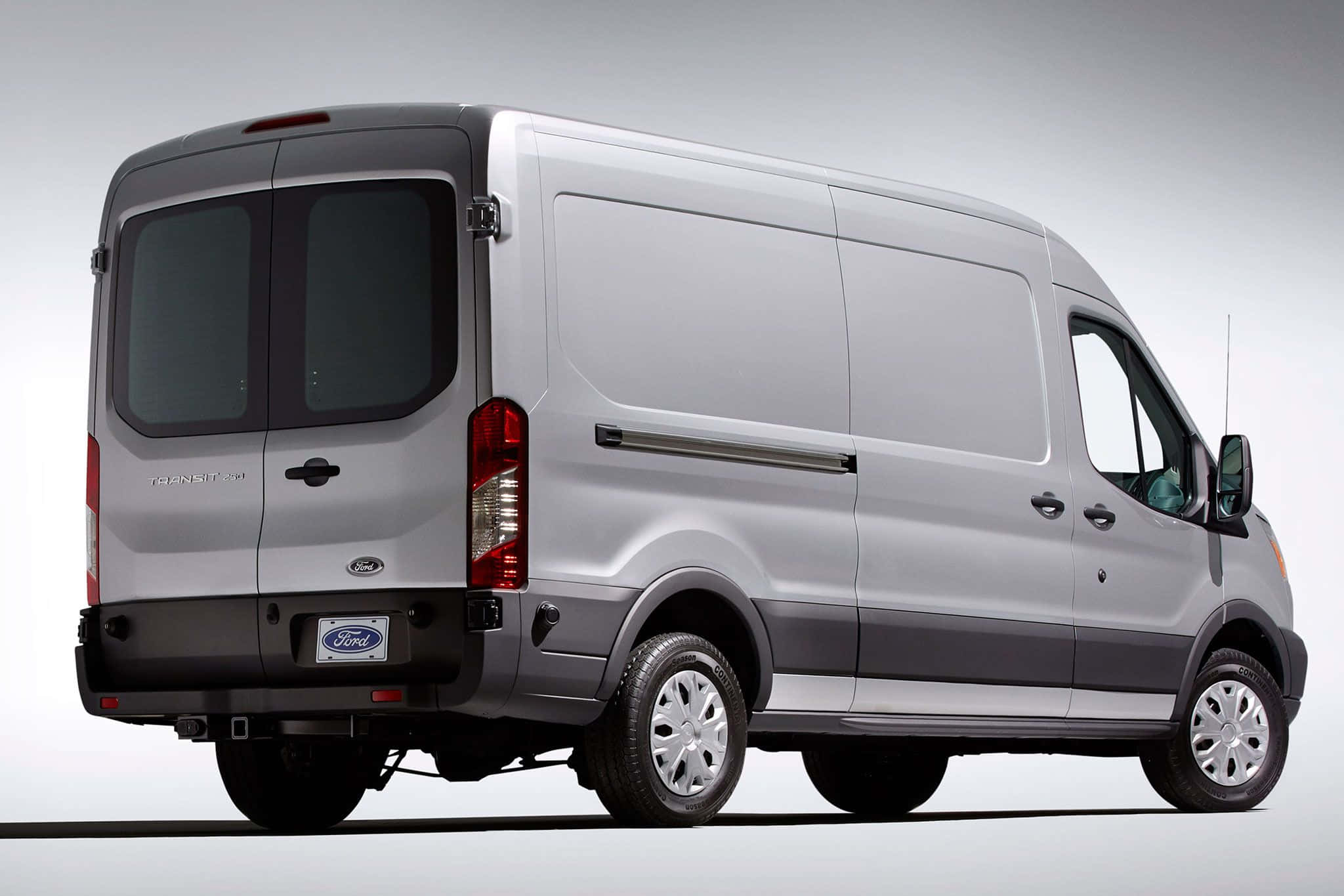 Ford Transit 桌布 壁紙 — 一架時尚的銀色福特 Transit 客貨車以四分之三後視角度展示，背景為乾淨的攝影棚。