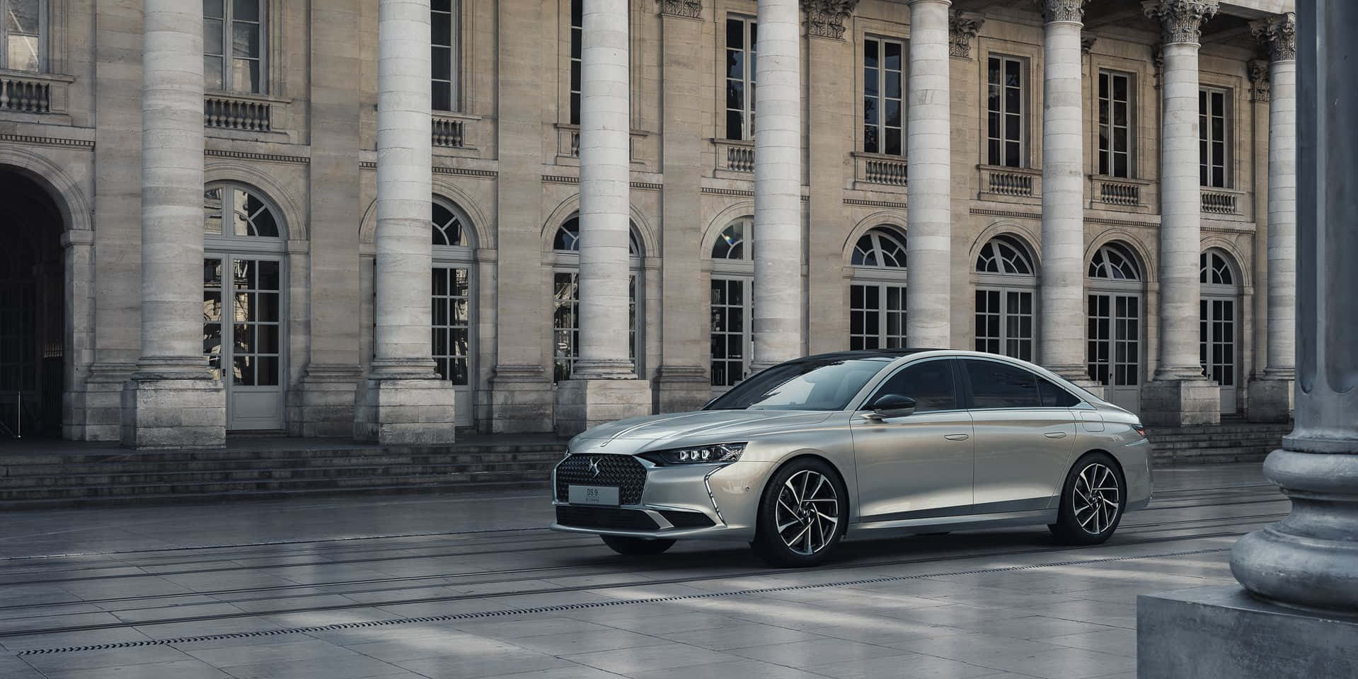 Ds Automobiles 桌布 壁紙 — 一架時尚的銀色轎車停在一棟宏偉的新古典主義建築前，建築有高大的柱子和拱形窗戶。