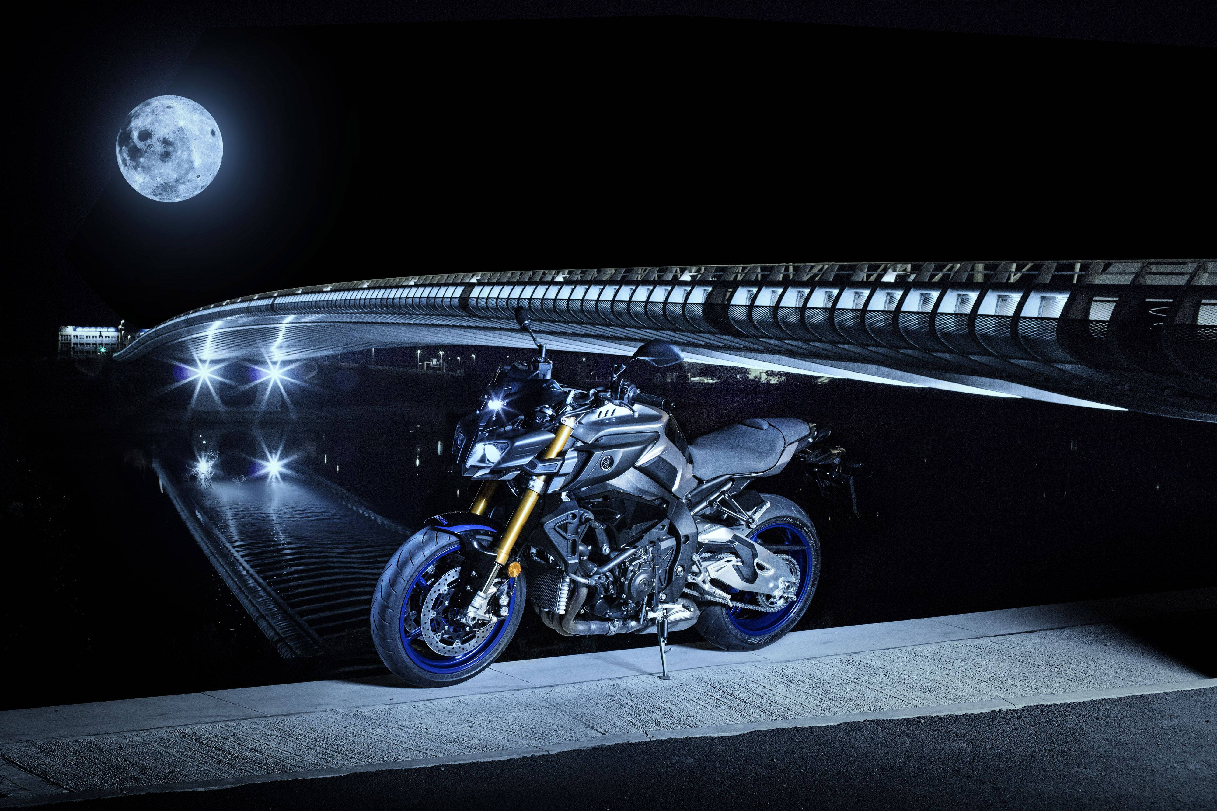 yamaha mt 15 桌布 壁紙 — 一架時尚的銀色電單車配藍色車輪，夜晚停在一條拱橋下，上方有一輪滿月。
