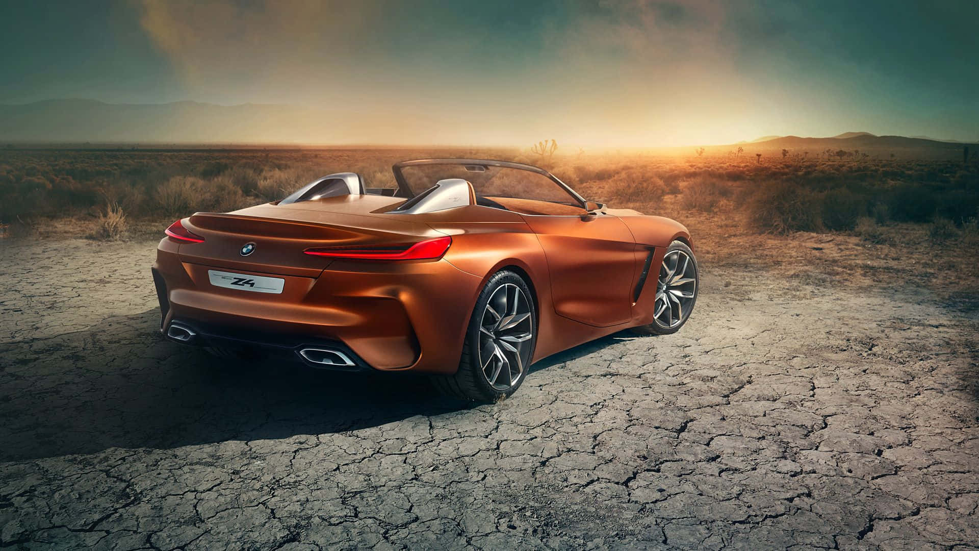 Bmw Z4 桌布 壁紙 — 一架時尚的銅色BMW Z4開篷跑車停泊在龜裂的沙漠地上，背景是金色的日落天空。