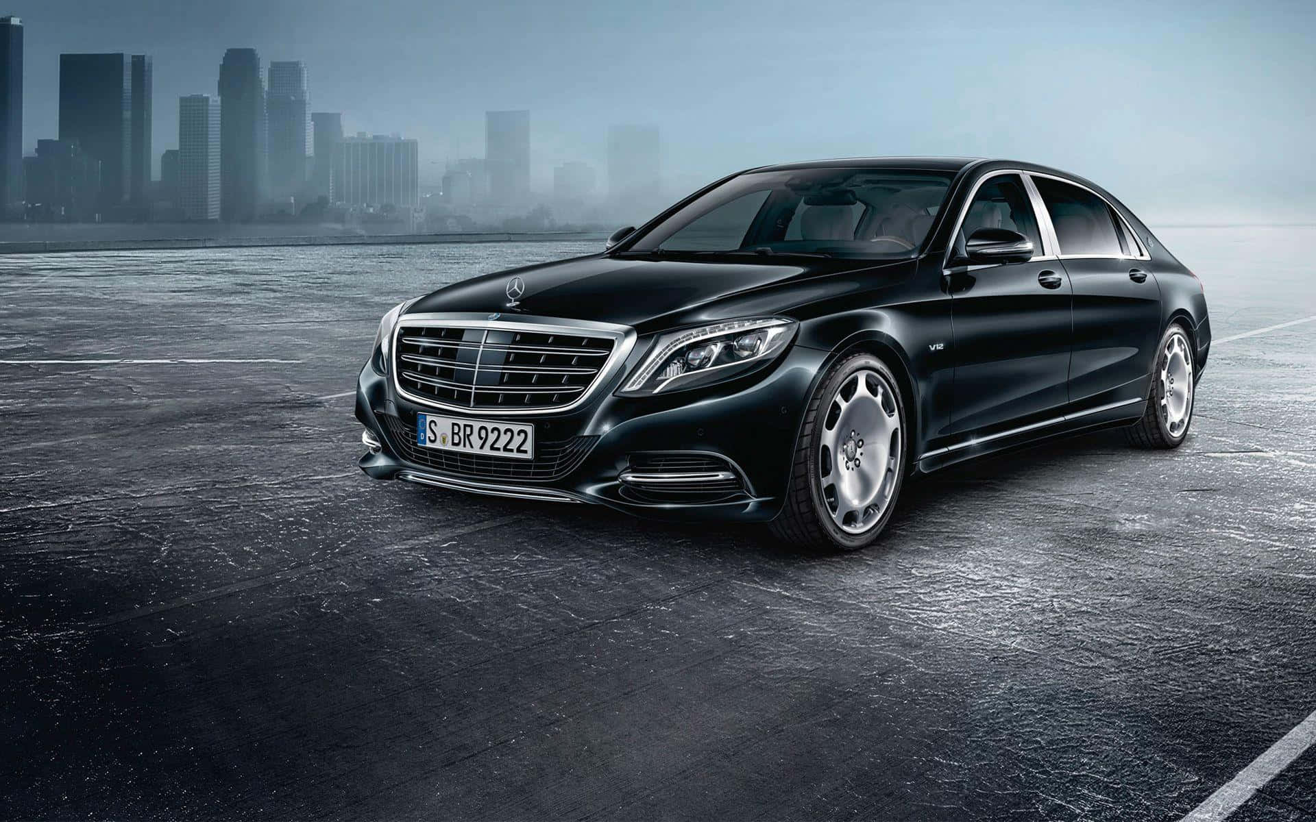 Maybach 桌布 壁紙 — 一架時尚的黑色 Mercedes-Maybach S-Class 轎車在濕漉漉的城市道路上閃耀，背景是朦朧的城市天際線。