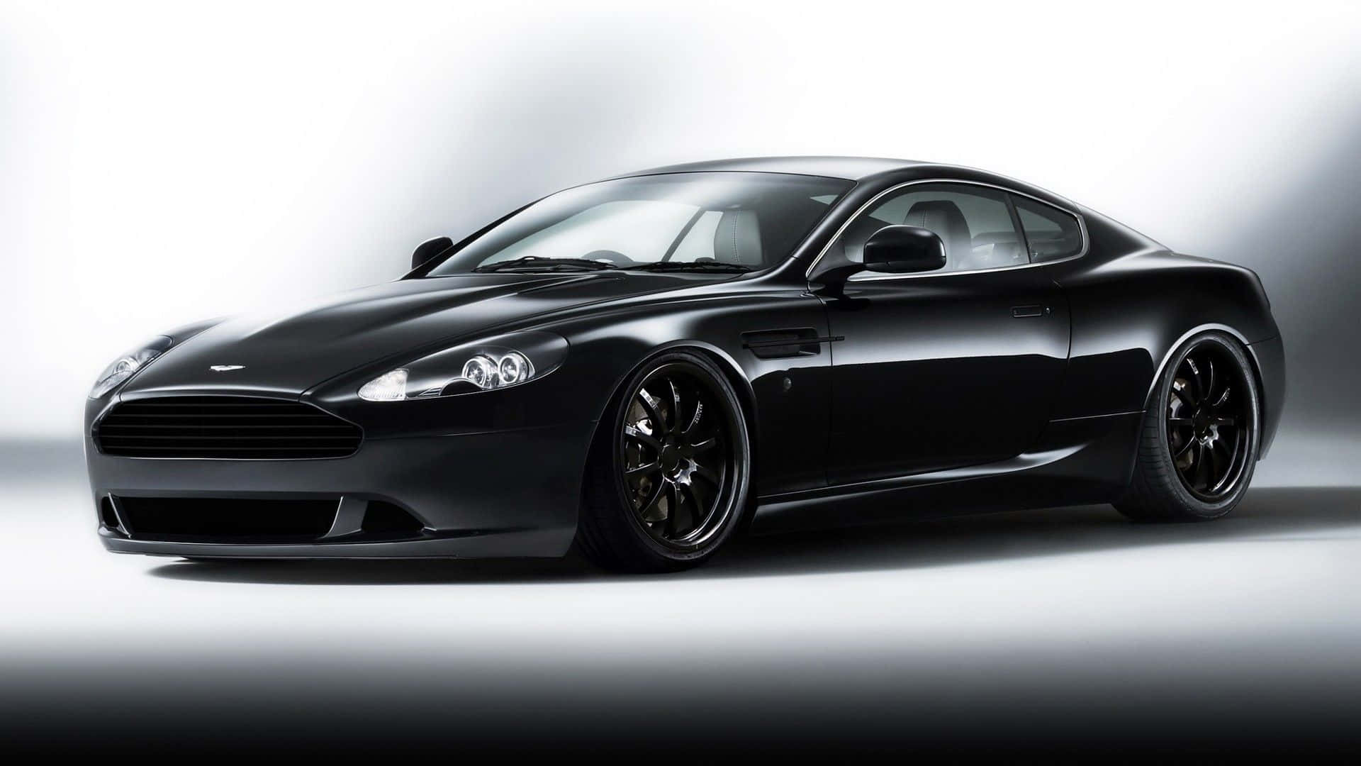 Aston Martin Db9 桌布 壁紙 — 一架時尚的黑色Aston Martin跑車在工作室燈光下閃閃發光，背景為簡約漸變色。