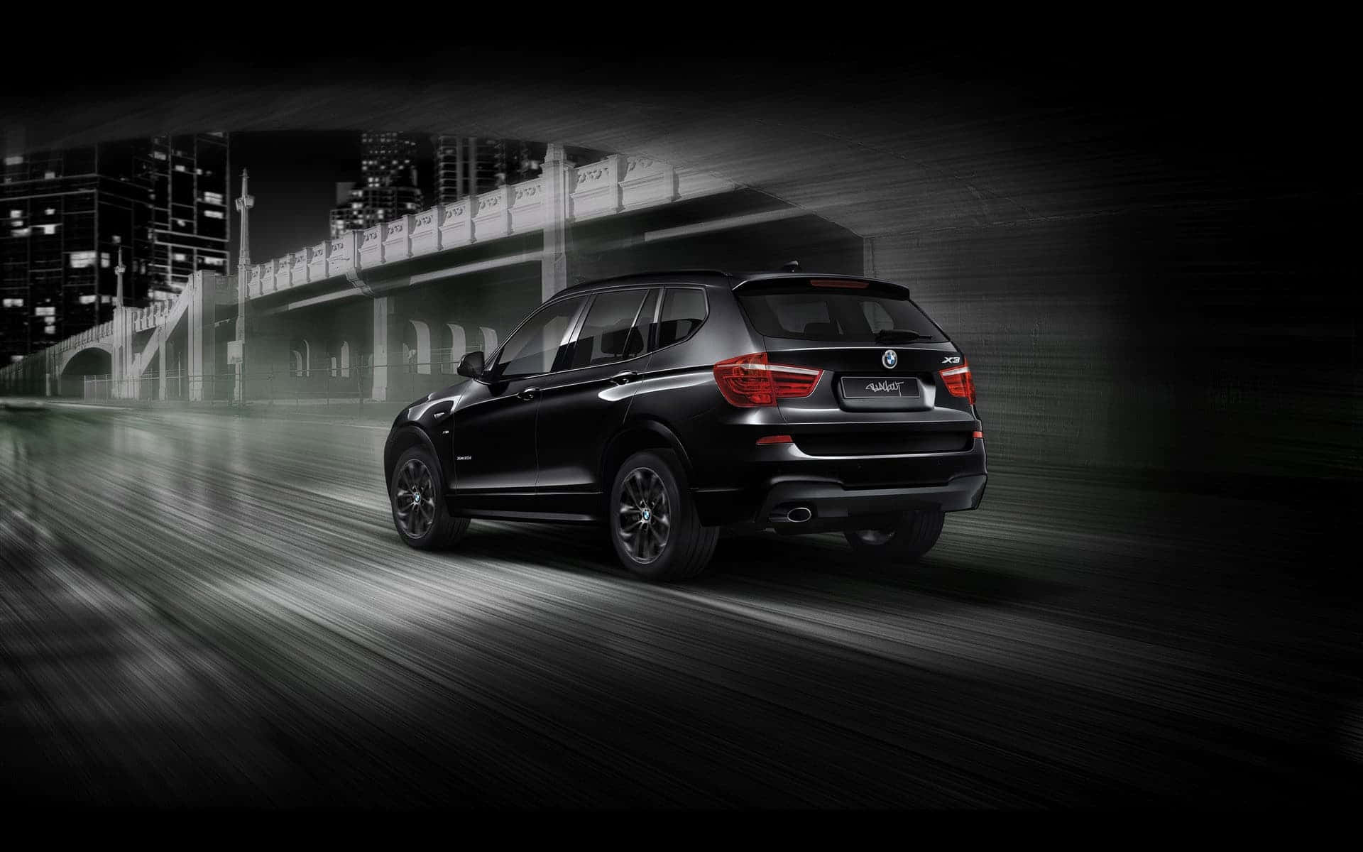 Bmw X3 桌布 壁紙 — 一架時尚的黑色BMW SUV在濕滑的市區隧道中疾馳，帶有動態模糊和發光的紅色尾燈。