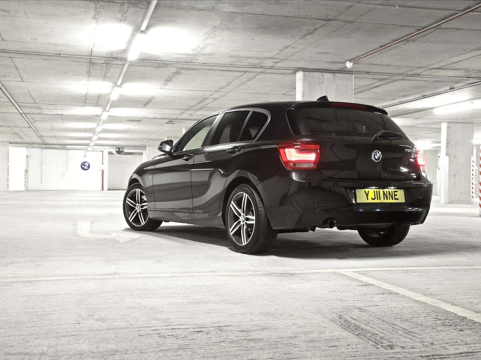 Bmw 1 Series 桌布 壁紙 — 一架時尚的黑色BMW掀背車停在光線昏暗的混凝土地下停車場，尾燈發光。