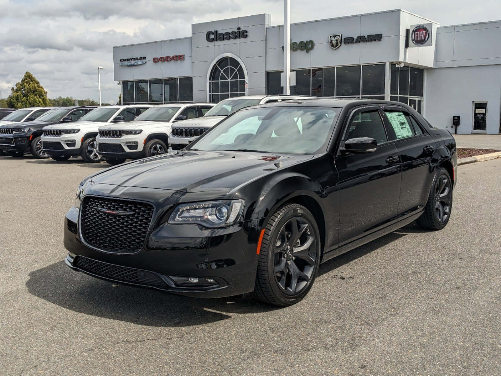 Chrysler 300 桌布 壁紙 — 一架時尚的黑色Chrysler 300房車在陰天下的汽車經銷商場地中閃閃發光，其他車輛和品牌標誌清晰可見。