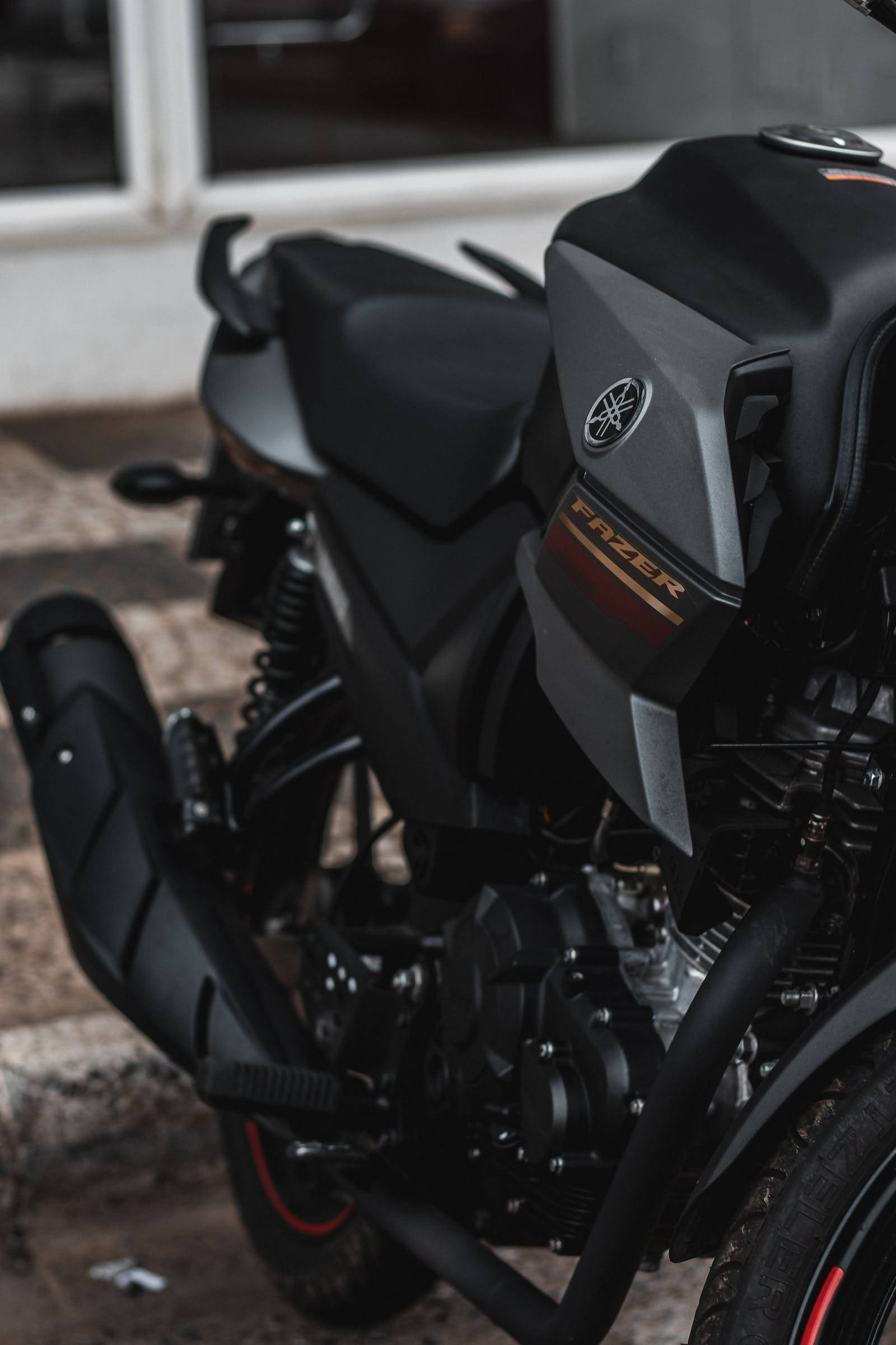 機車 桌布 壁紙 — 一架時尚的黑色Yamaha Fazer電單車停在石頭表面上，背景是模糊的建築物。