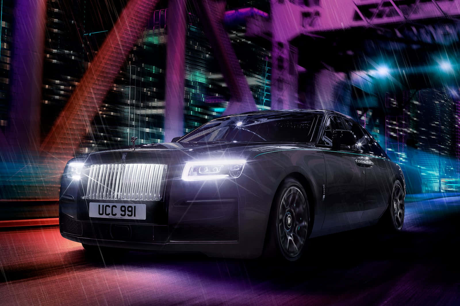 Rolls Royce 桌布 壁紙 — 一架時尚的黑色勞斯萊斯 Ghost 在夜晚穿過霓虹燈閃爍、雨水浸濕的城市景觀，發光的燈光在潮濕的街道上反射。