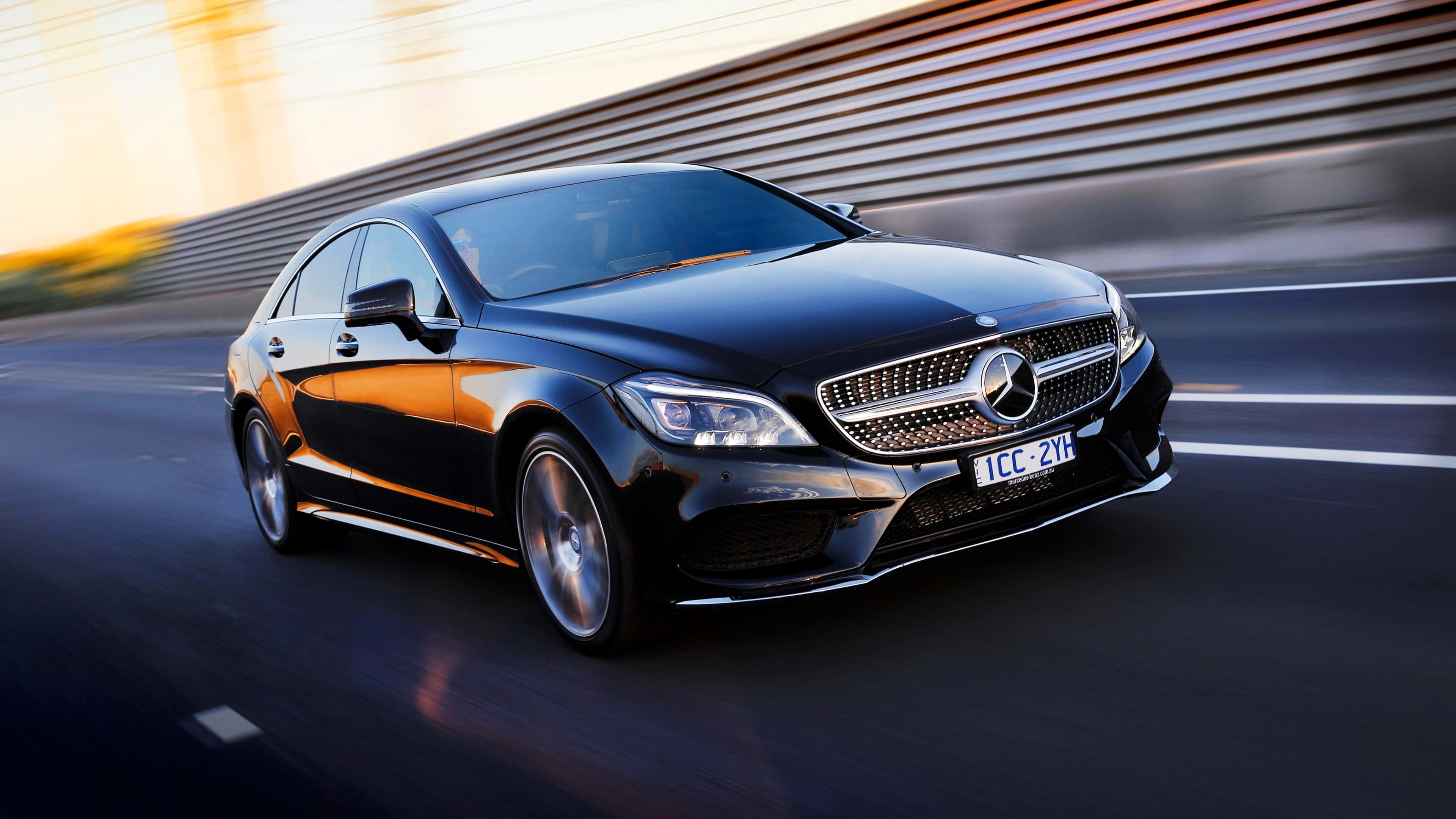 4K Mercedes 桌布 壁紙 — 一架時尚的黑色平治房車在日落時分沿高速公路飛馳，背景帶有動態模糊效果。