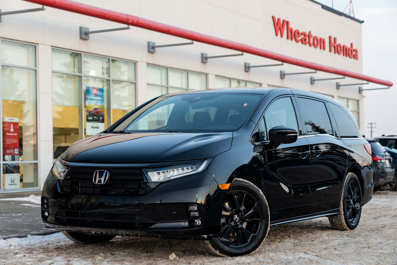Honda Odyssey 桌布 壁紙 — 一架時尚的黑色本田Odyssey小型貨車在日光下閃閃發光，停放在Wheaton本田經銷商前，地上有雪塊。