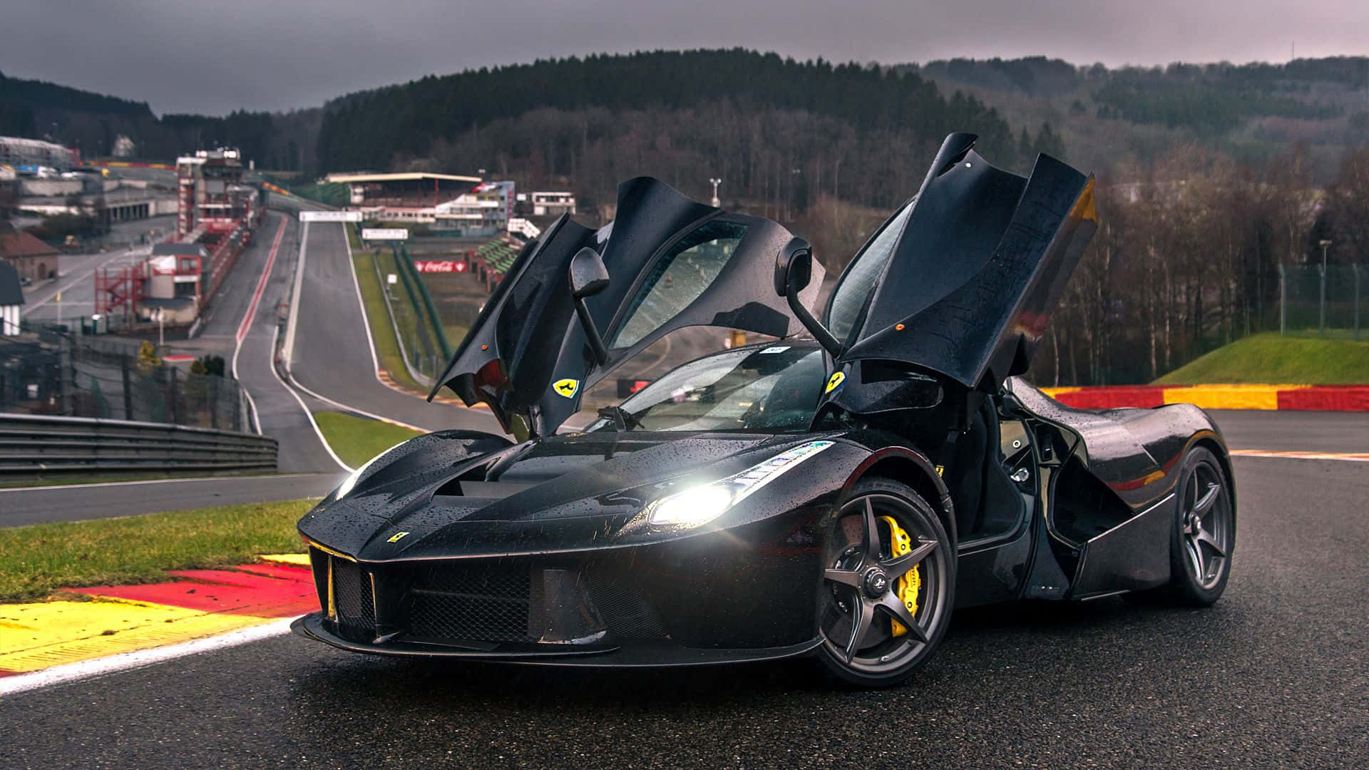 Ferrari Laferrari 桌布 壁紙 — 一架時尚的黑色法拉利 LaFerrari 打開鷗翼車門，停在潮濕的賽車場上，天空多雲。