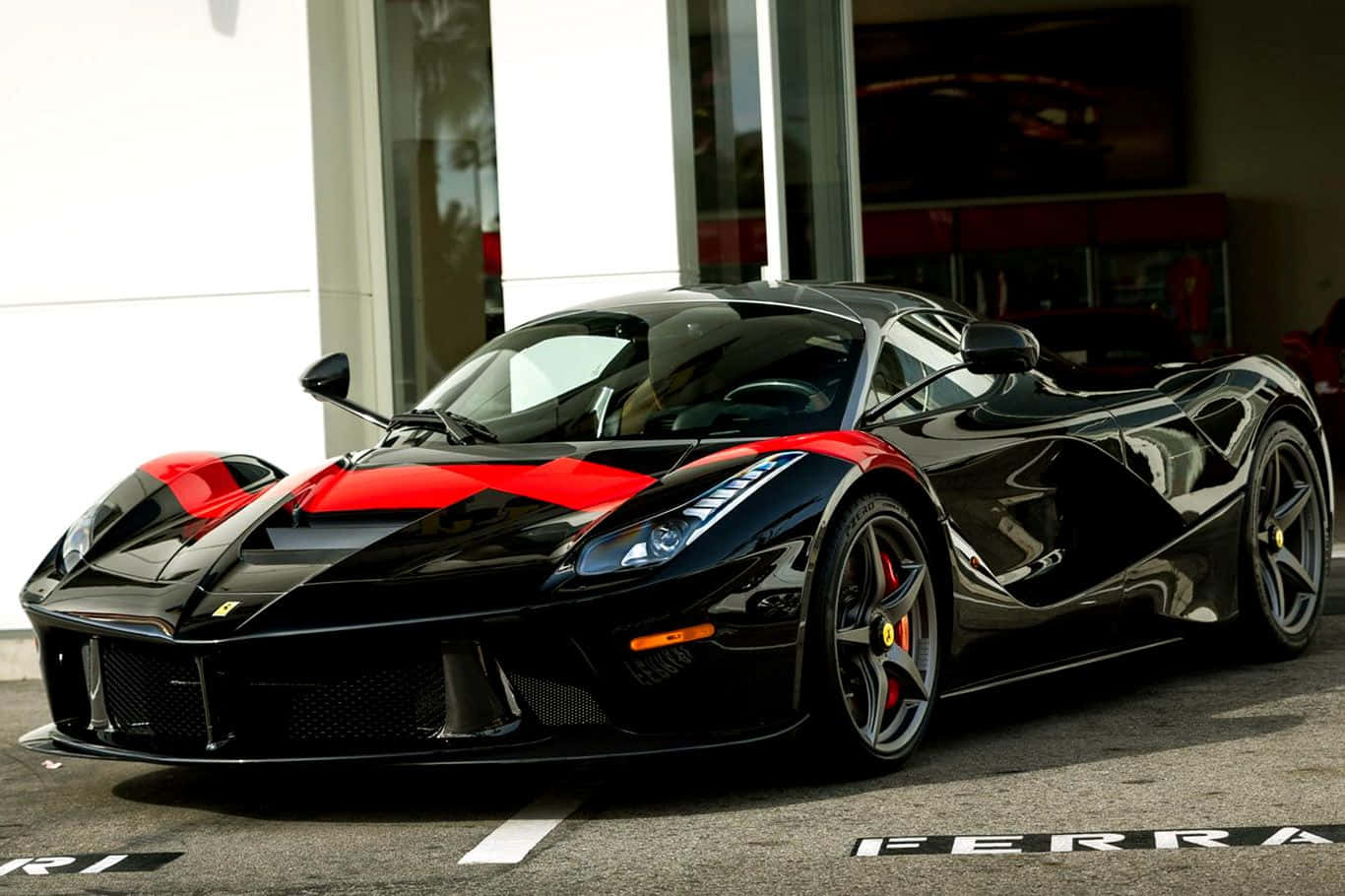 Ferrari Laferrari 桌布 壁紙 — 一架時尚的黑色法拉利LaFerrari帶有醒目紅色點綴，在明亮的日光下閃耀，停泊在現代化陳列室前。
