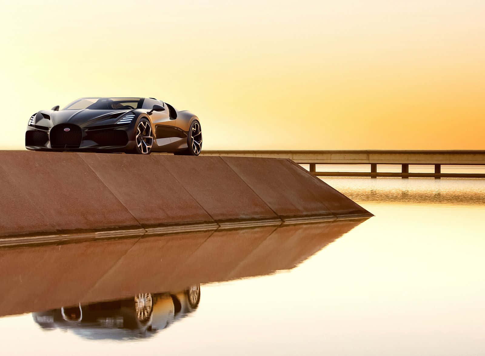 Sports Car 桌布 壁紙 — 一架時尚的黑色跑車停泊在混凝土邊緣上，下方平靜的水面倒映著金色的日落天空。