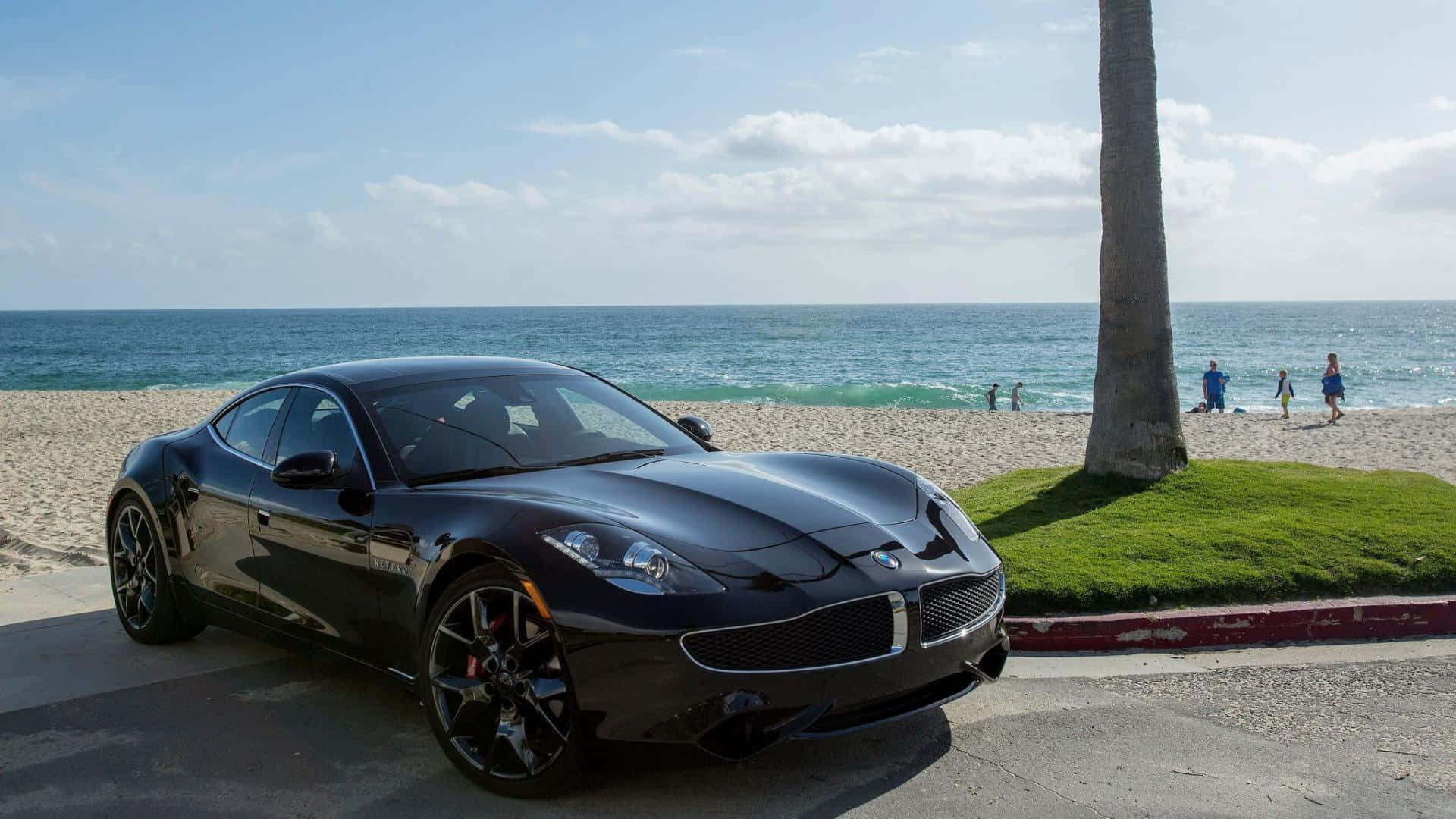 Fisker 桌布 壁紙 — 一架時尚的黑色跑車停泊在陽光明媚的海濱道路上，背景有棕櫚樹和海浪。