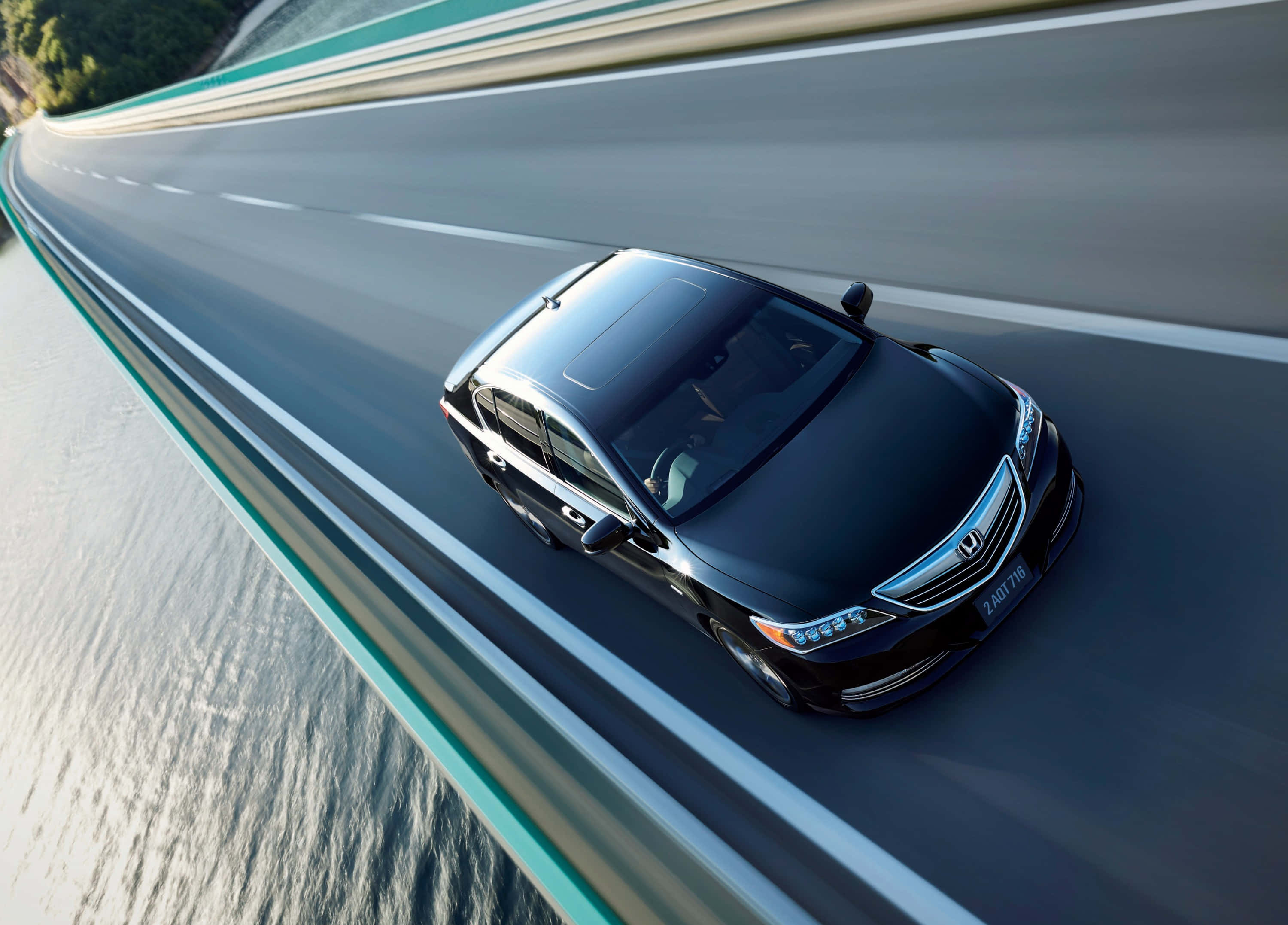 Honda Legend 桌布 壁紙 — 一架時尚的黑色轎車沿著蜿蜒的海岸高速公路行駛，配有藍綠色護欄和下方閃爍的大海。