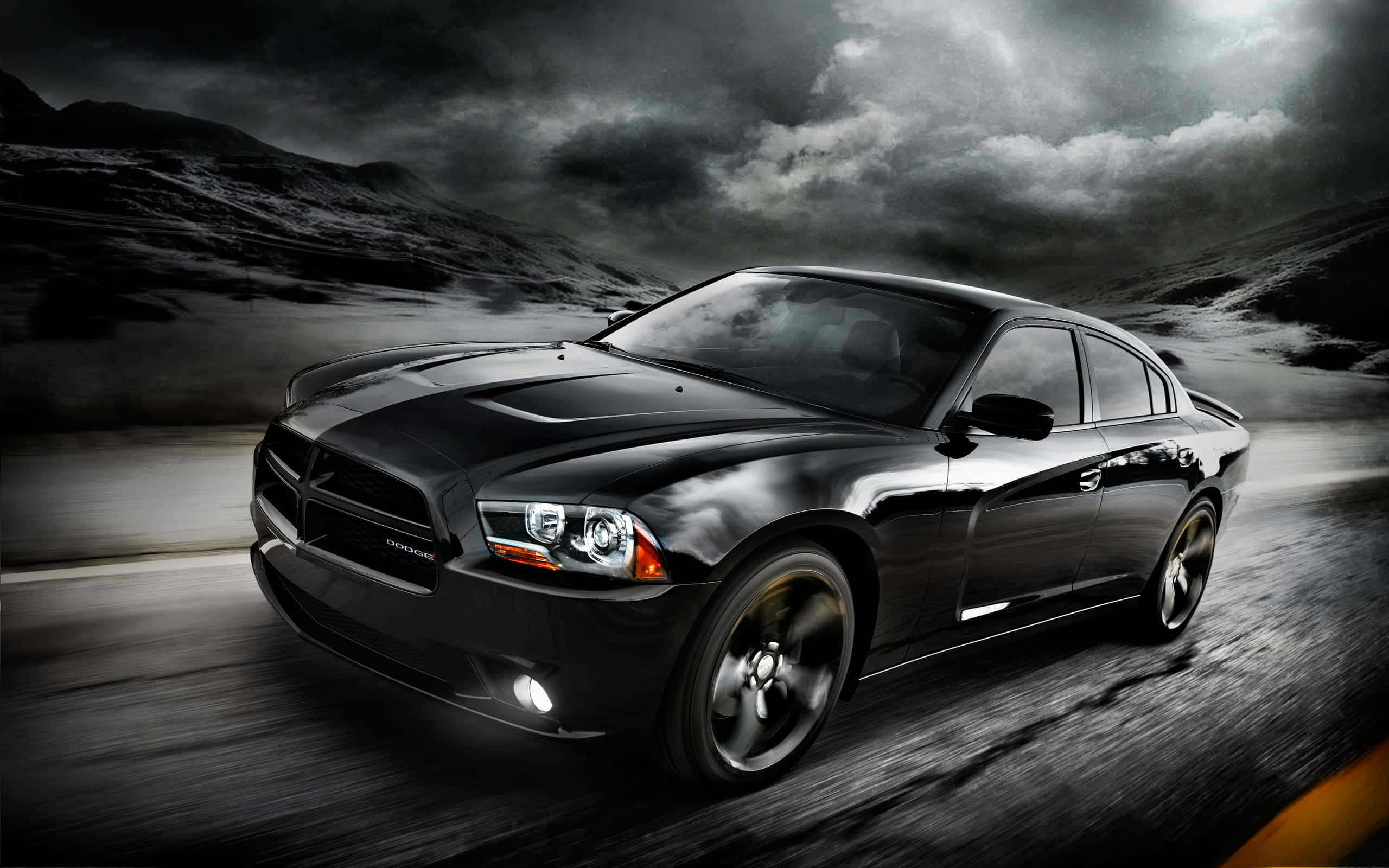 Dodge Charger 桌布 壁紙 — 一架時尚的黑色道奇挑戰者，在風暴籠罩的山口疾馳，頭頂是戲劇性的雲層。