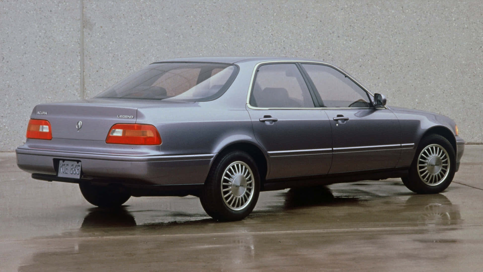 Acura Legend 桌布 壁紙 — 一架時尚銀色Acura Legend房車停泊在濕滑路面上，背景是灰色混凝土牆。