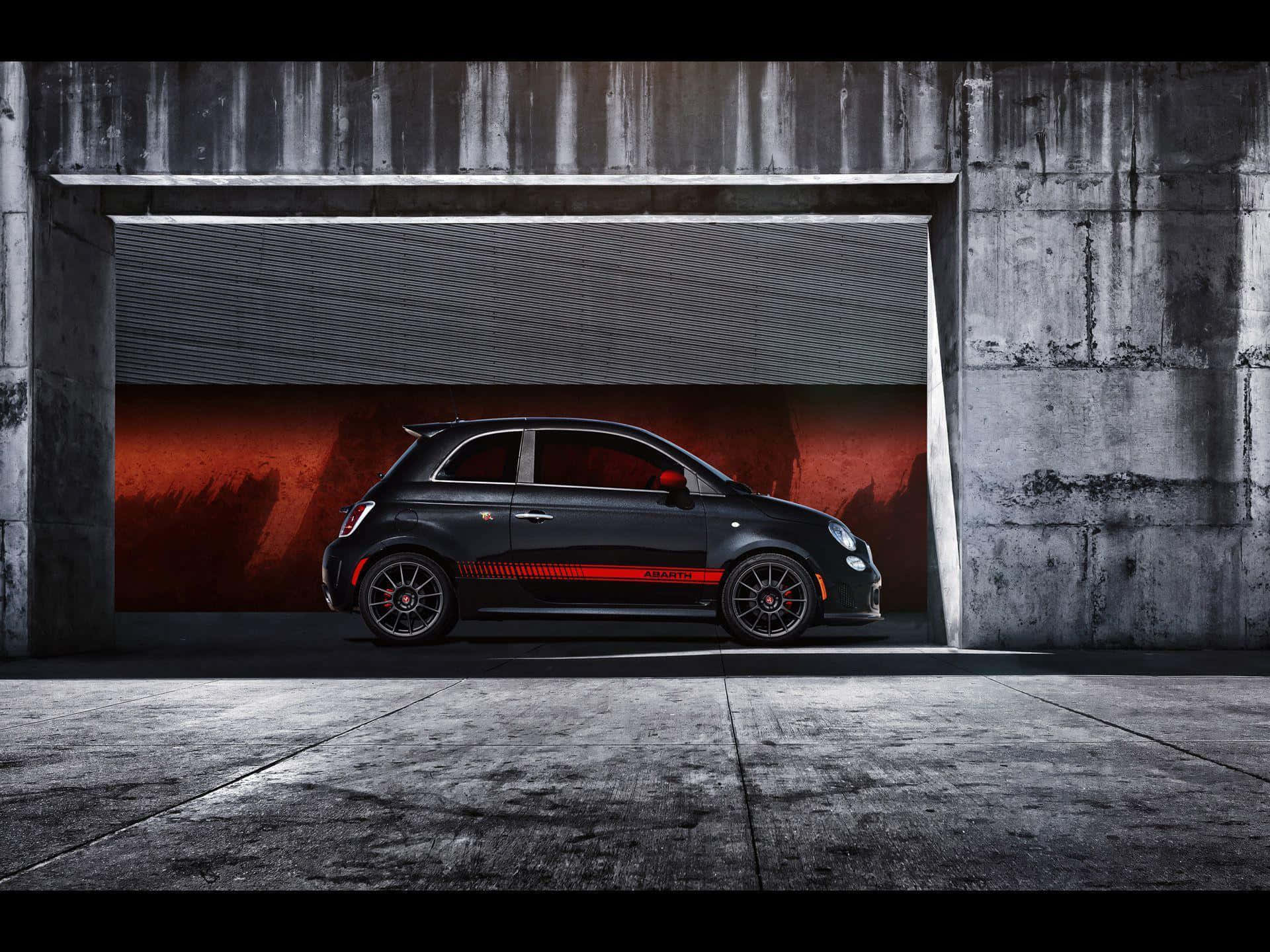 Abarth 桌布 壁紙 — 一架時尚黑色 Fiat Abarth 跑車帶有紅色點綴，停放在一個帶有戲劇性紅色背景的混凝土車庫中。