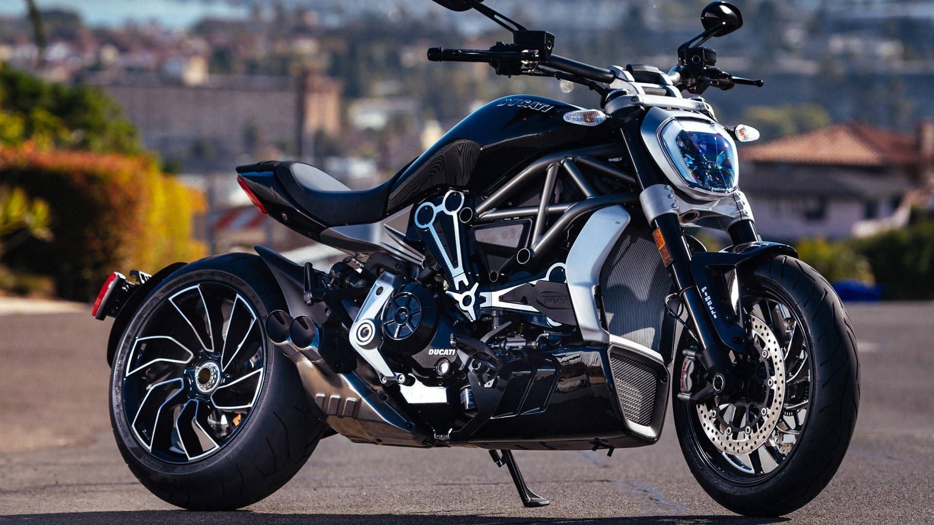 機車 桌布 壁紙 — 一架時尚黑色Ducati電單車，帶有外露的銀色車架和複雜的機械細節，停泊在陽光普照的街道上。